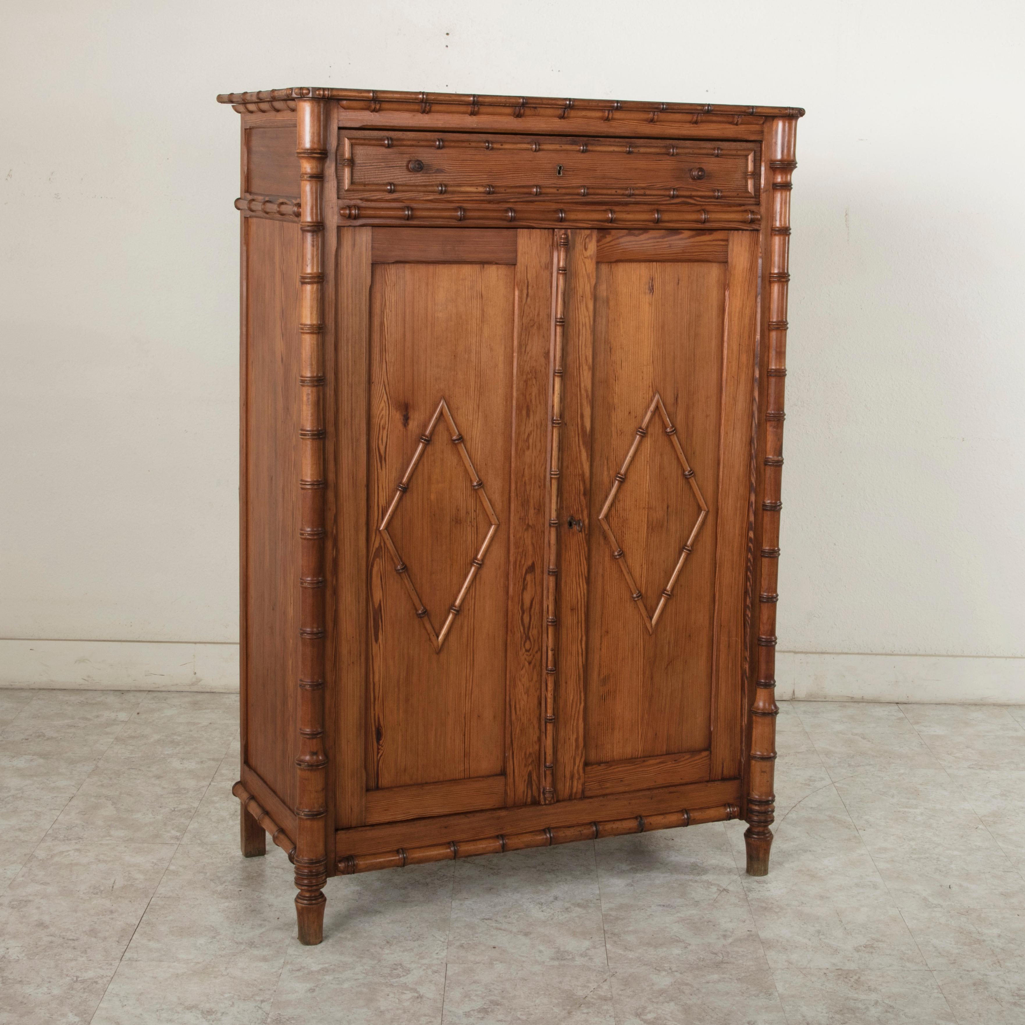 This turn of the 20th century French colonial style pitch pine armoirette features faux bamboo corners and edges constructed of maple. Its two paneled doors are detailed with faux bamboo diamonds and open to reveal an interior with three adjustable