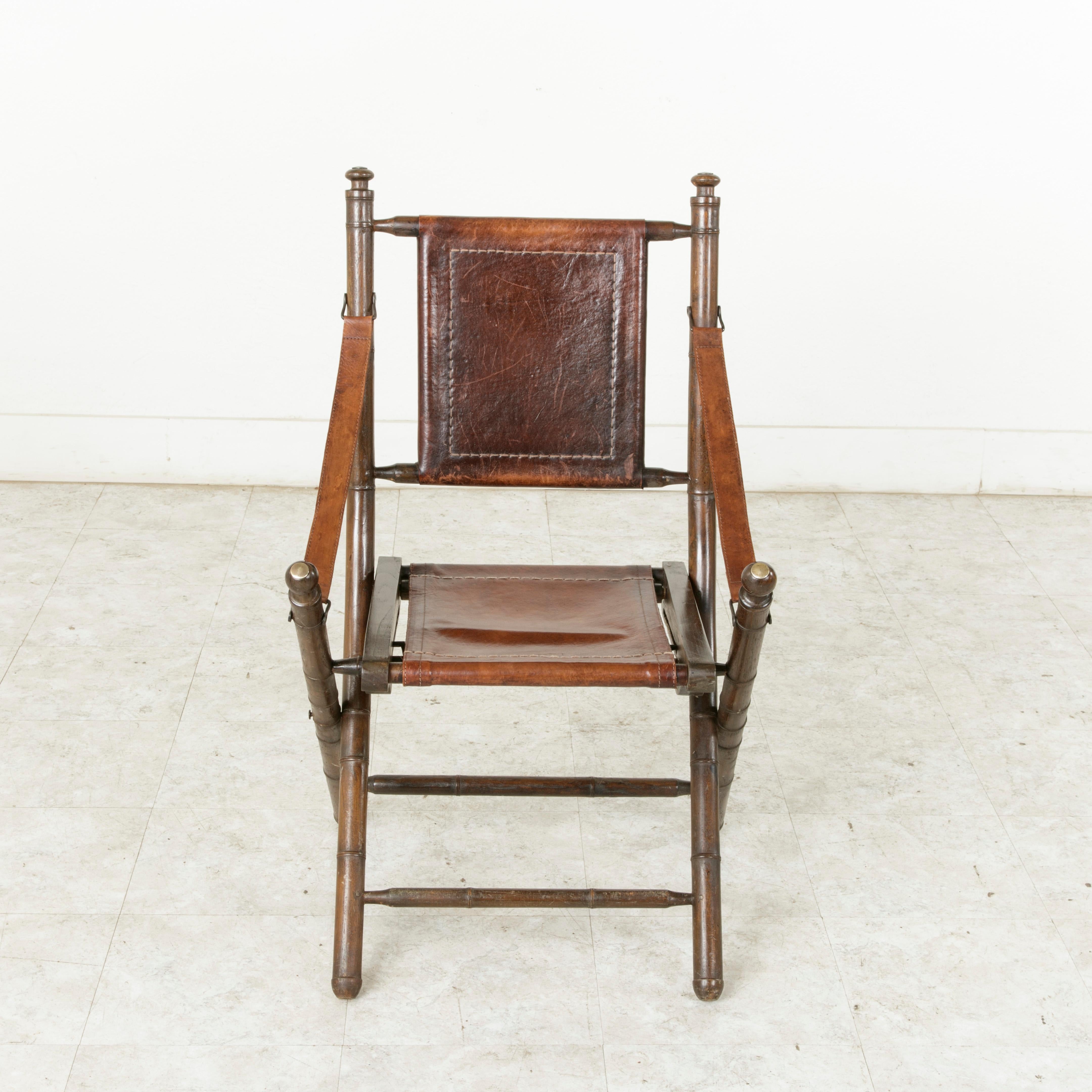 Dieser klappbare Liegestuhl aus französischem Nussbaumholz von der Wende zum 20. Jahrhundert hat gedrechselte Beine und Rückenlehnenstützen aus Bambusimitat. Der Stil aus der französischen Kolonialzeit:: als sich das französische Reich bis nach