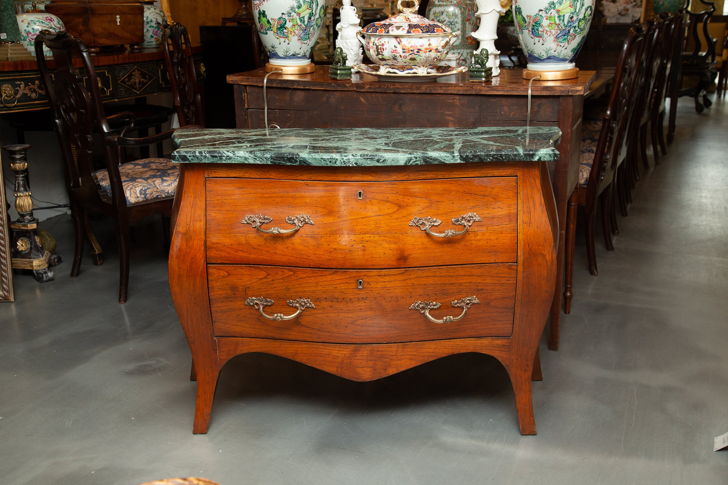 This is a very quiet French Louis XV fruitwood bombe commode. The Verdi green marble top rests over two long drawers. the case piece is raised on splay feet flanking a shaped apron, early 20th century.