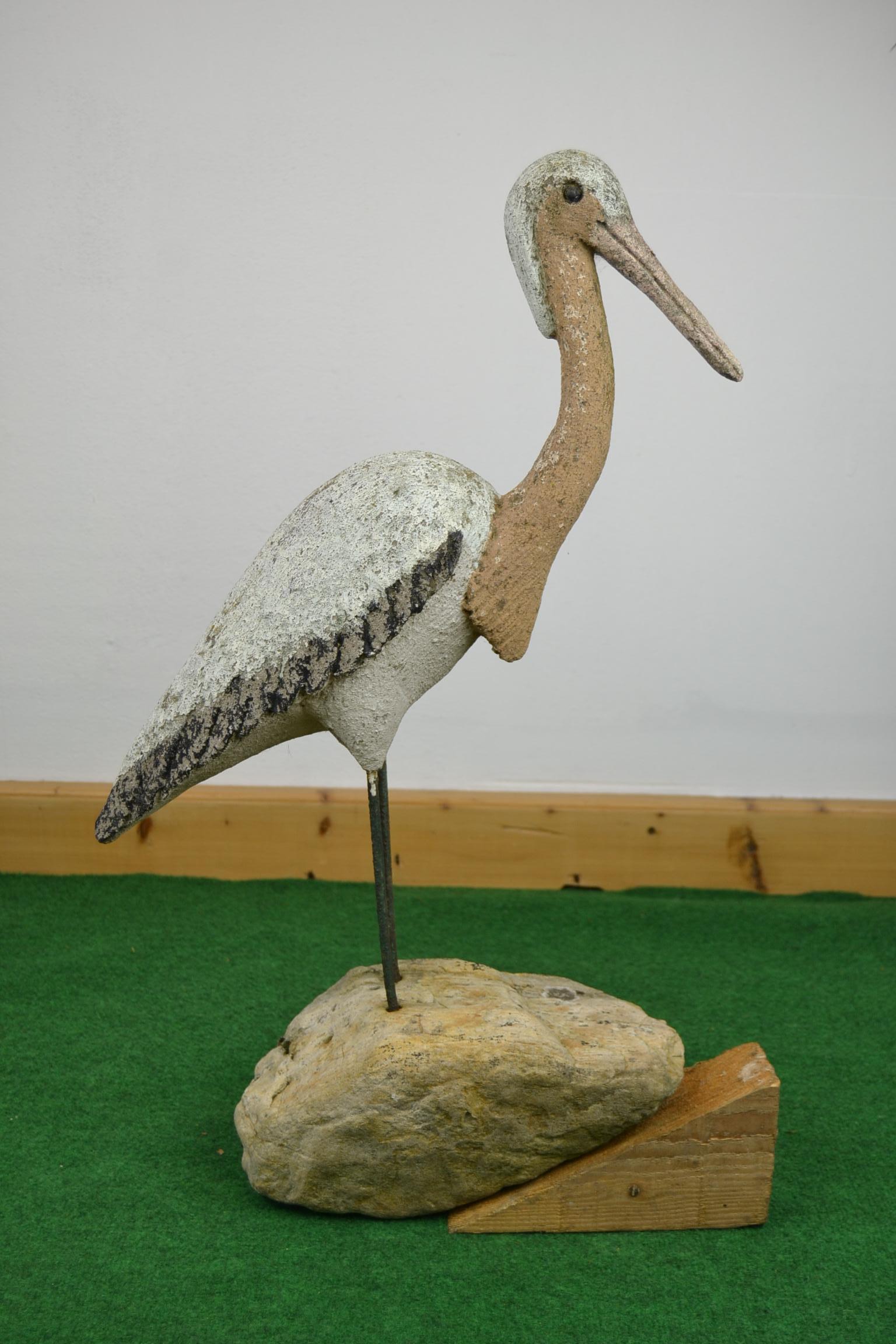 French vintage concrete bird sculpture.
This eye-catching garden sculpture in the shape of a bird is made of painted stone or painted concrete with iron legs mounted in a stone or rock. This garden bird sculpture still has his original