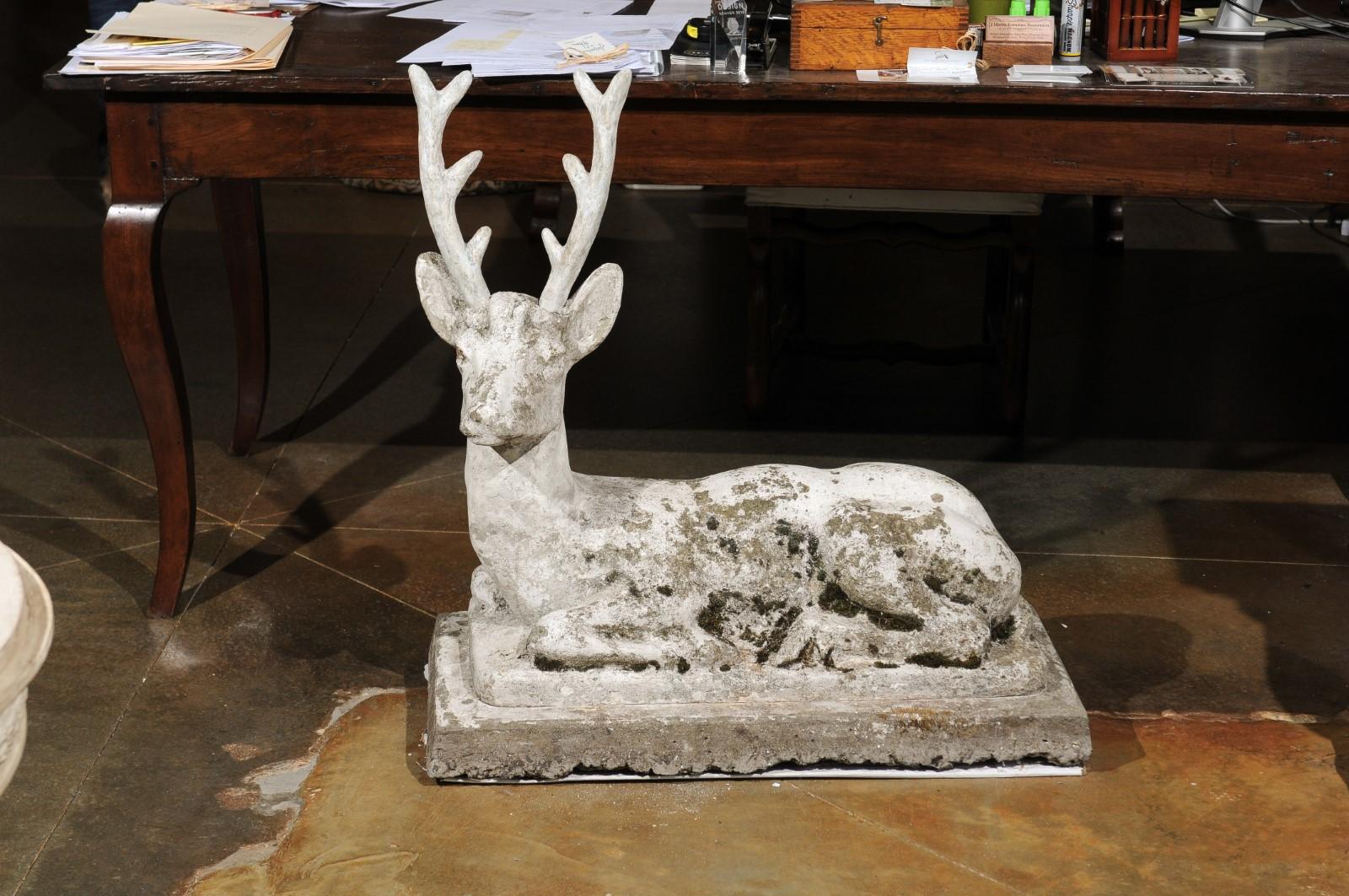 A French concrete deer sculpture from the early 20th century, with nicely weathered patina. Born in the early years of the 20th century during the Belle Époque era, this concrete sculpture depicts a reclining deer, resting on a stepped base. Topped