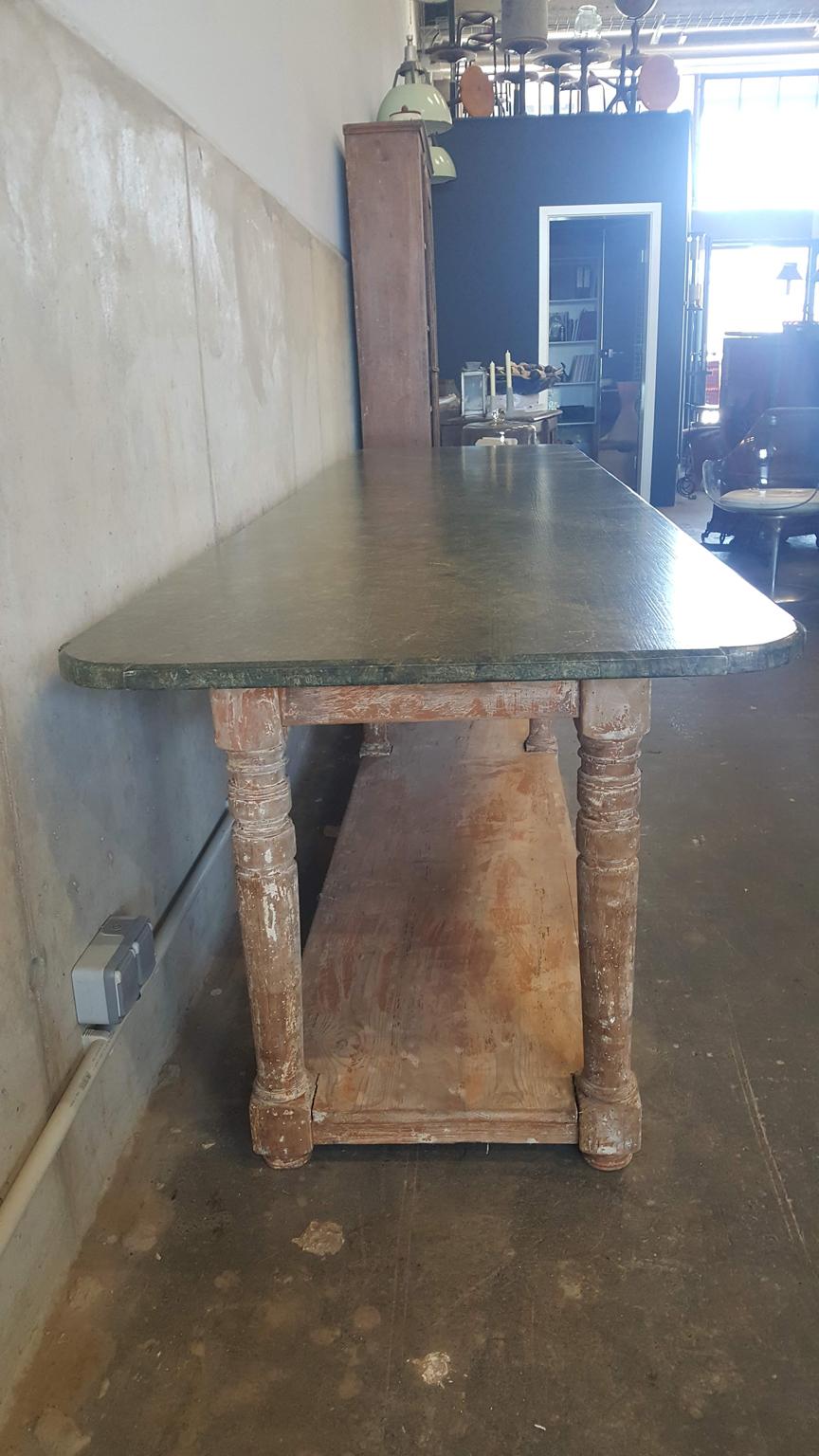 Beautiful and rare table from a French confectionery. The long table has its original color. The color scheme of the table top is to imitate green marble. The base is rust brown / salmon colored. In the lower area is a typical shelf. Although the