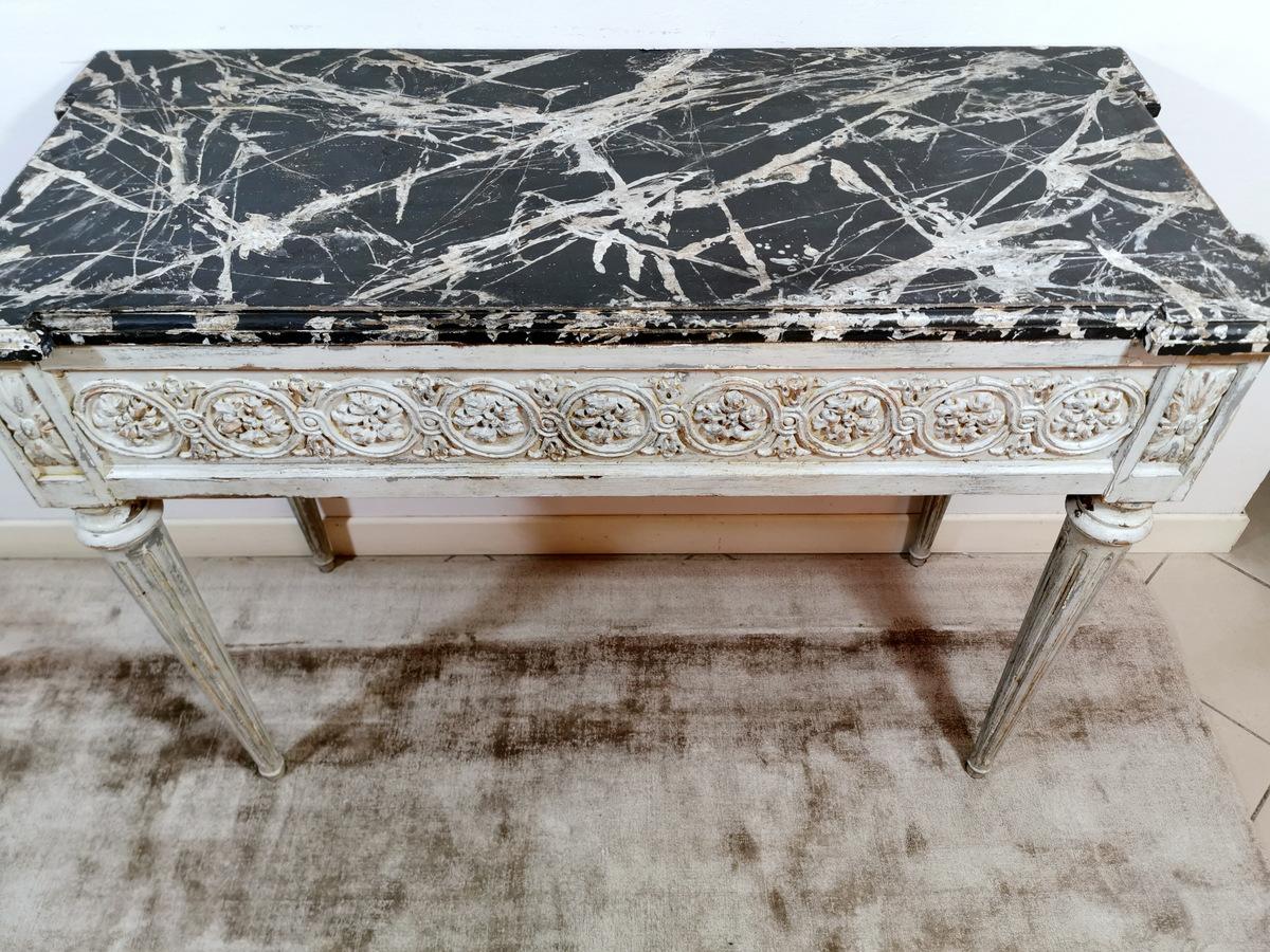 French console in lacquered wood and skillfully carved by hand with high relief motifs. The console tabletop is lacquered with Fake Marble (Finto Marmo), one of the most ancient decorative techniques to embellish wooden elements. The lacquered