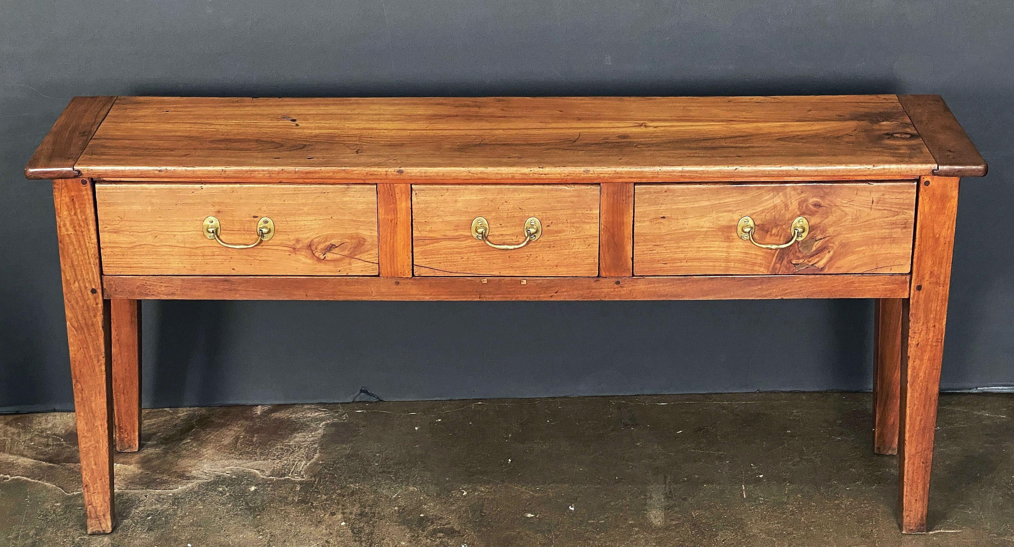 A handsome French console sideboard (or serving table) of patinated cherrywood, featuring a rectangular plank top over a frieze with three drawers, each with brass hardware pulls, and resting on tapering square legs.

H 29 3/16 in x W 65 in x D
