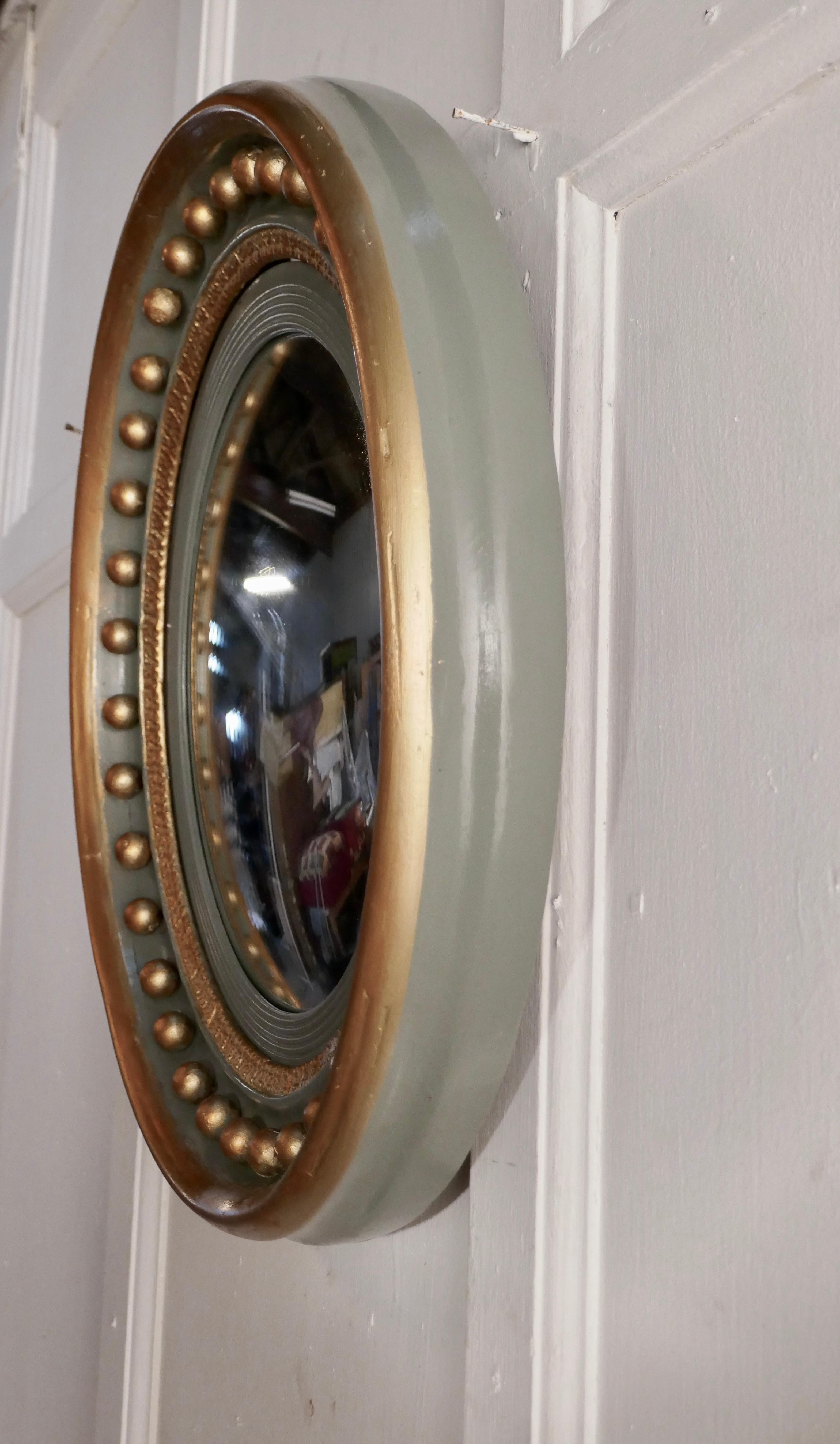 French convex green and gold wall mirror

This pretty mirror has a deep gilt and grey/green circular frame decorated with large spheres, the convex glass is held by a reeded mount

The wide 3.5” round frame is in sound condition as is the