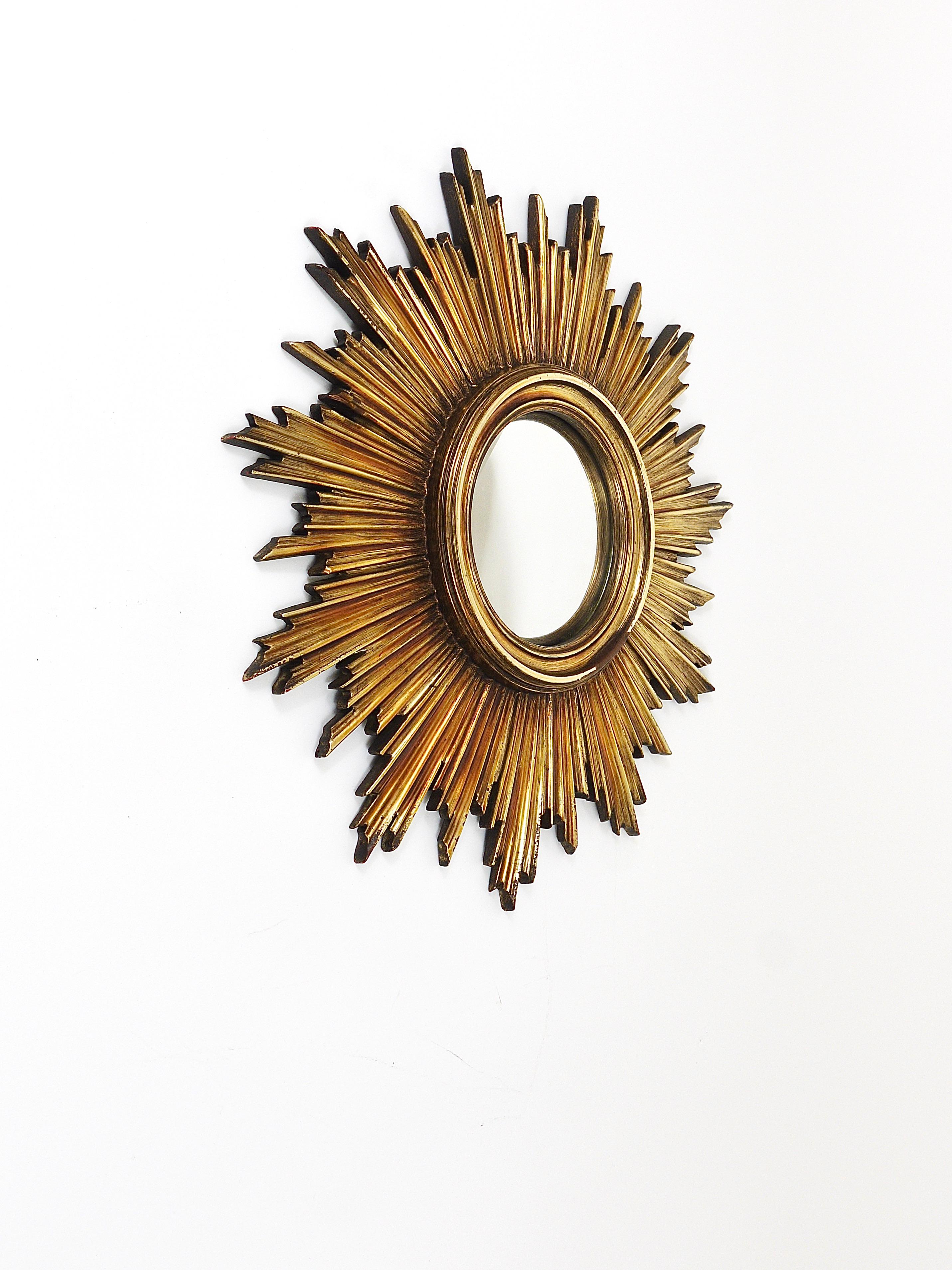 A very beautiful and decorative golden mid-century sunburst starburst mirror. Made in France in the 1960s. Made of resin, still with original convex mirror glass. In good condition. Total diameter 18“, the diameter of the mirror itself is 5 2/3“.