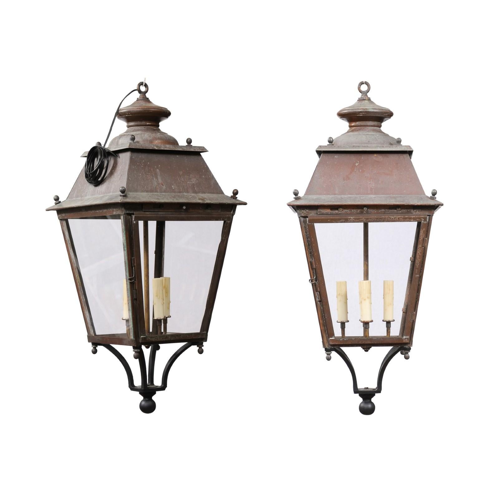 Two French copper lanterns from the 20th century, with four lights, glass panels, petite finial and rustic character. They are priced and sold each. Emanating a timeless rustic charm, these French copper lanterns from the 20th century are a perfect