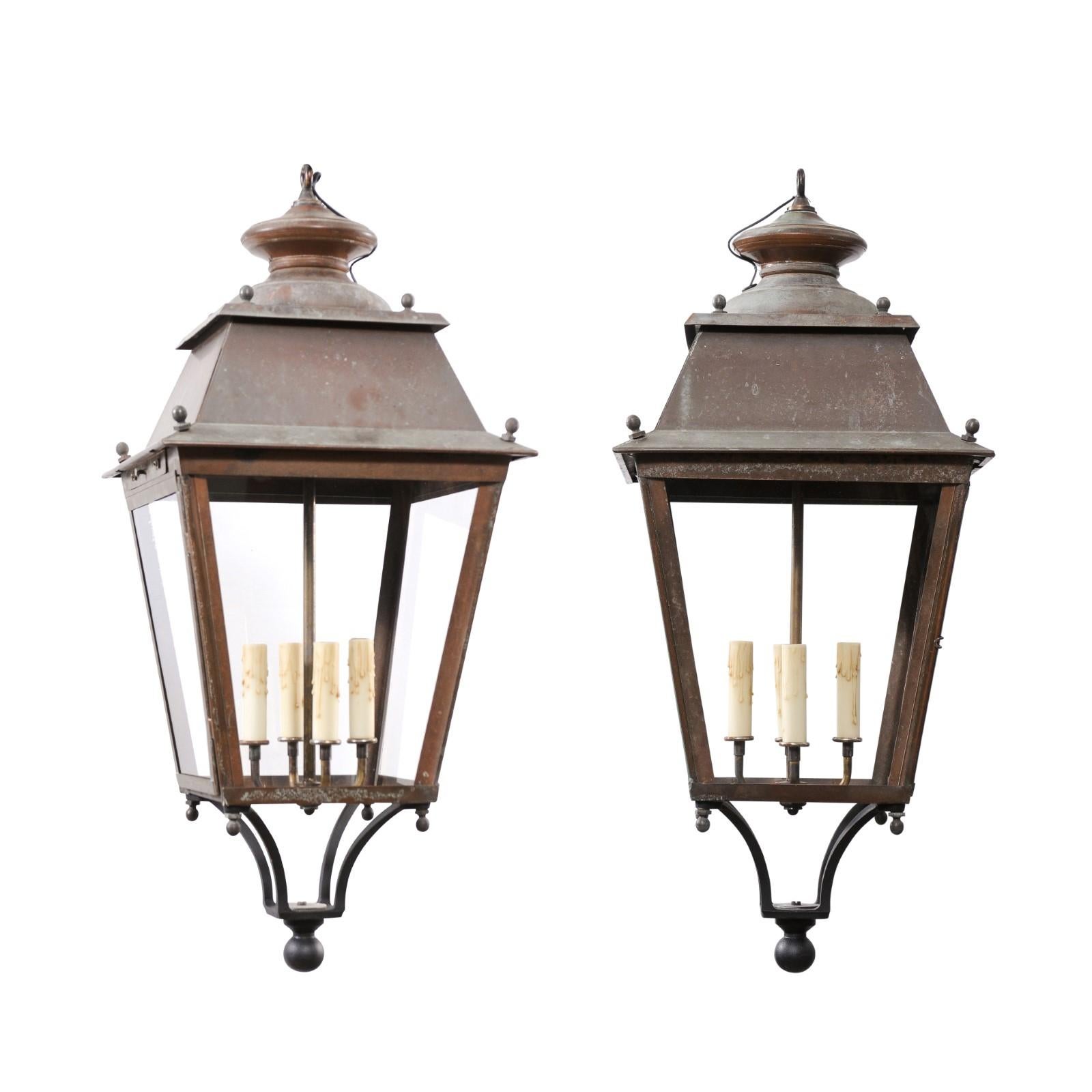 Two French copper four-light lanterns from the 20th century with glass panels, tapering silhouettes and petite spheres. These two French copper lanterns from the 20th century, each featuring four lights, present an elegant lighting solution with