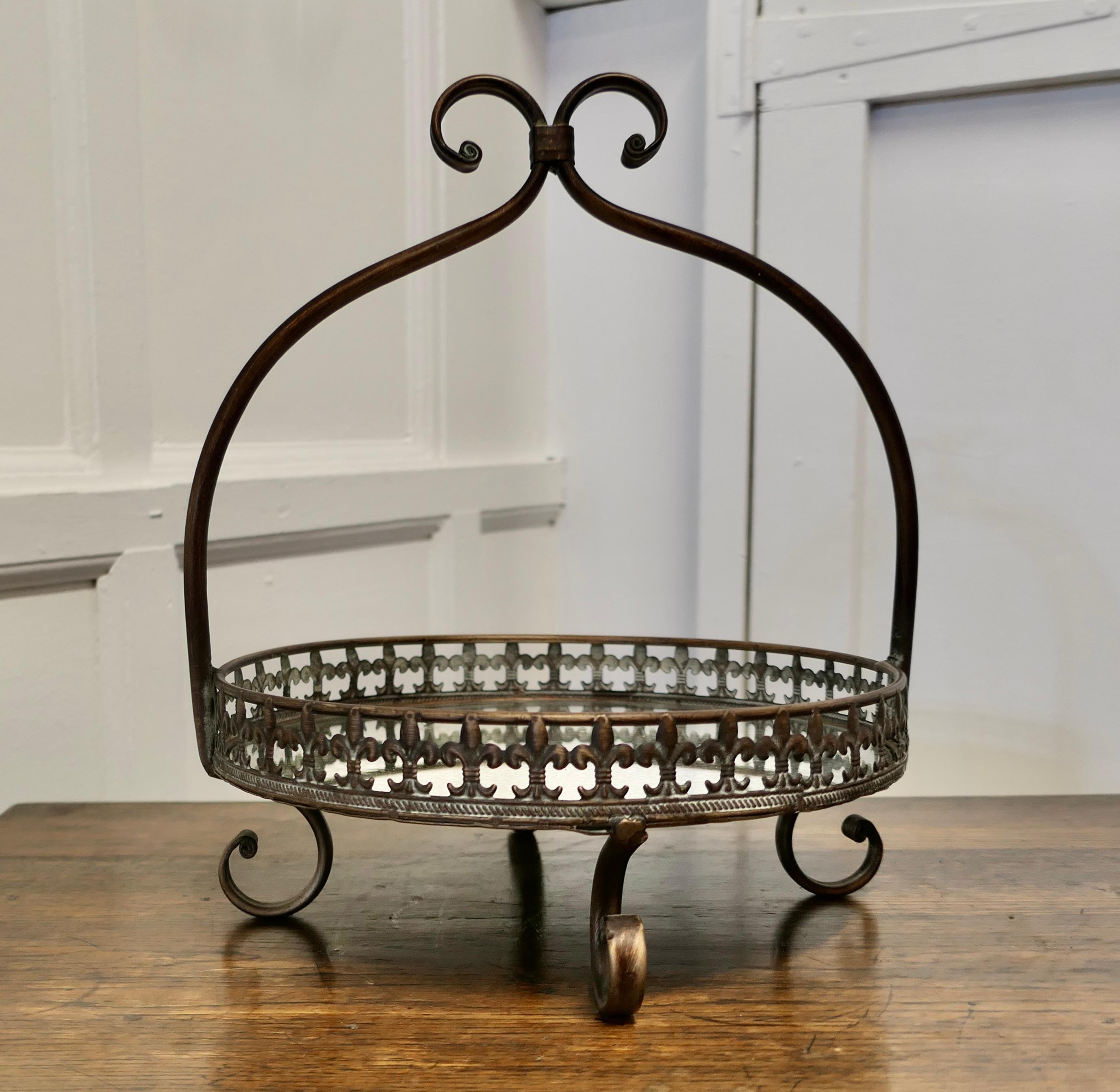 French Copper and Mirrored Bottomed Cake Stand

A pretty Cake stand with an arched handle, the stand sits on 4 curled feet which match the twist of the handle
The bottom of the stand is made of aged mirror and has a fleur des lys gallery around
The