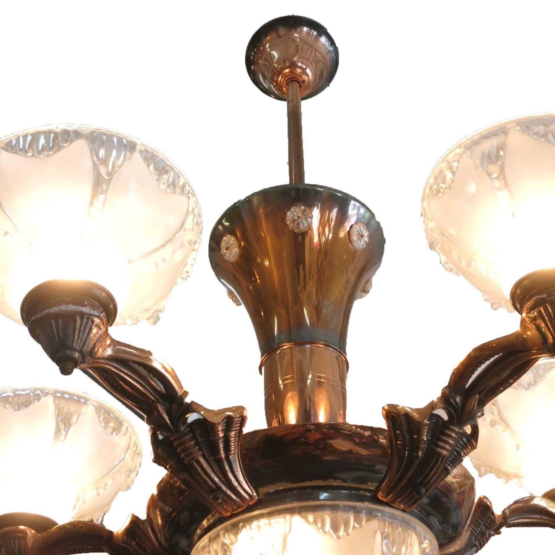 This French Art Deco copper chandelier comes with a five-arm design each containing frosted molded glass shades made by Ezan. The chandelier features a copper body featuring a center cylinder that branches out to 5 arms with an overhead dome for 6