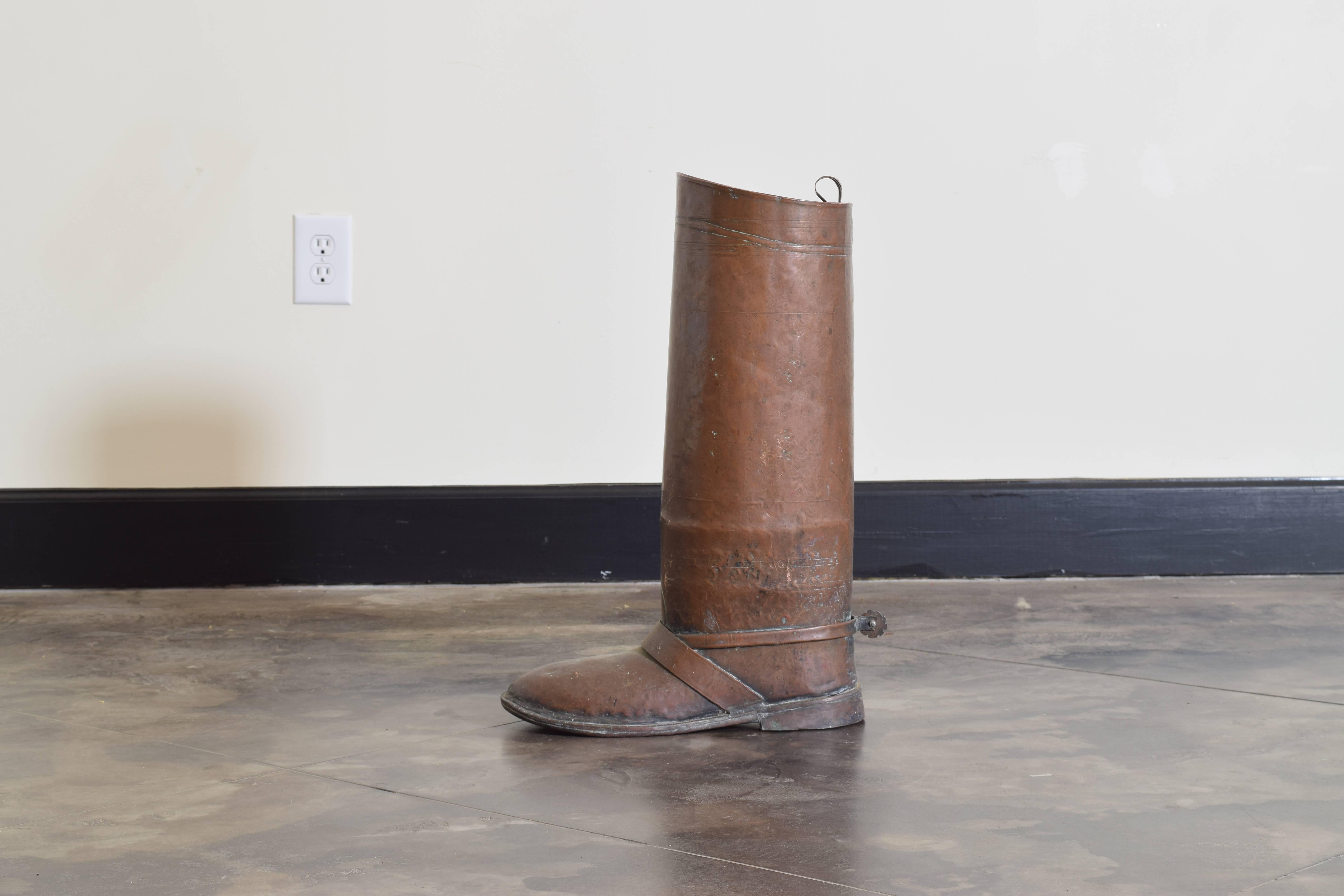 The umbrella stand in the shape of a soldier's riding boot, complete with strap detailing and spur, retaining antique patina.