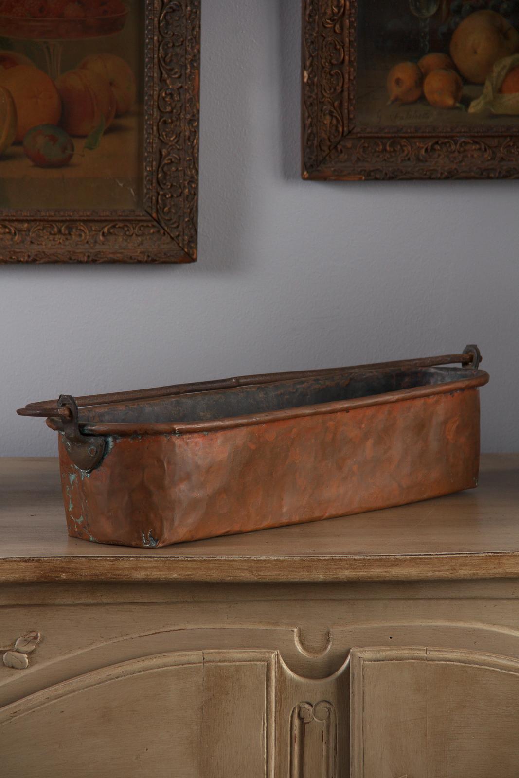 A wonderful rustic copper and iron poissoniere fish kettle from France, 19th century. The hand-hammered and brazed copper trough has a turned over lip which holds an iron rod frame. A swinging wrought iron handle stretches the length of the
