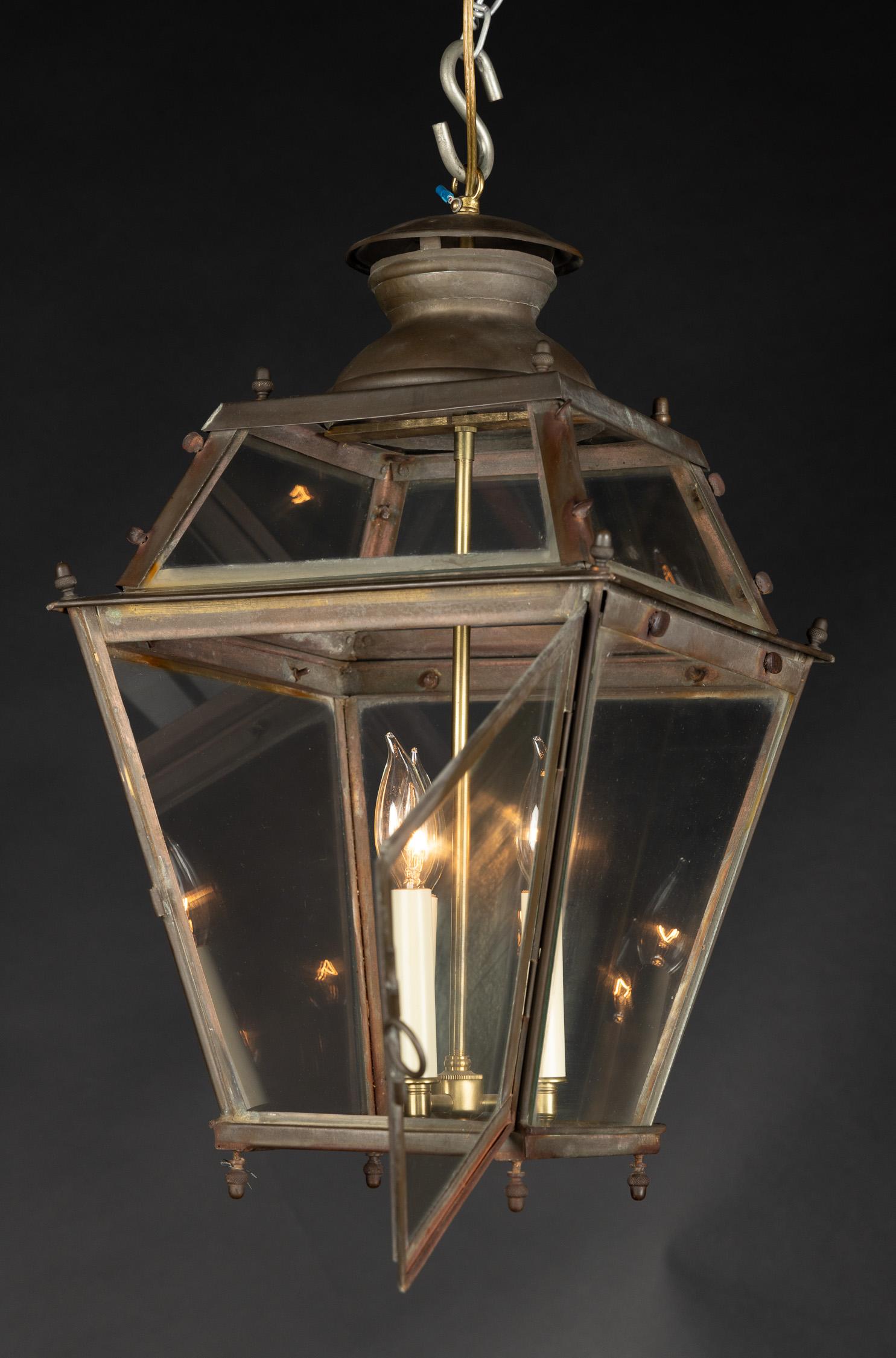 This beautiful copper lantern features glass panes and is adorned with acorn finials at all four corners of top, middle, and bottom. The French antique piece dates back to the Early 19th century and plays host to a unique glass top as well as a
