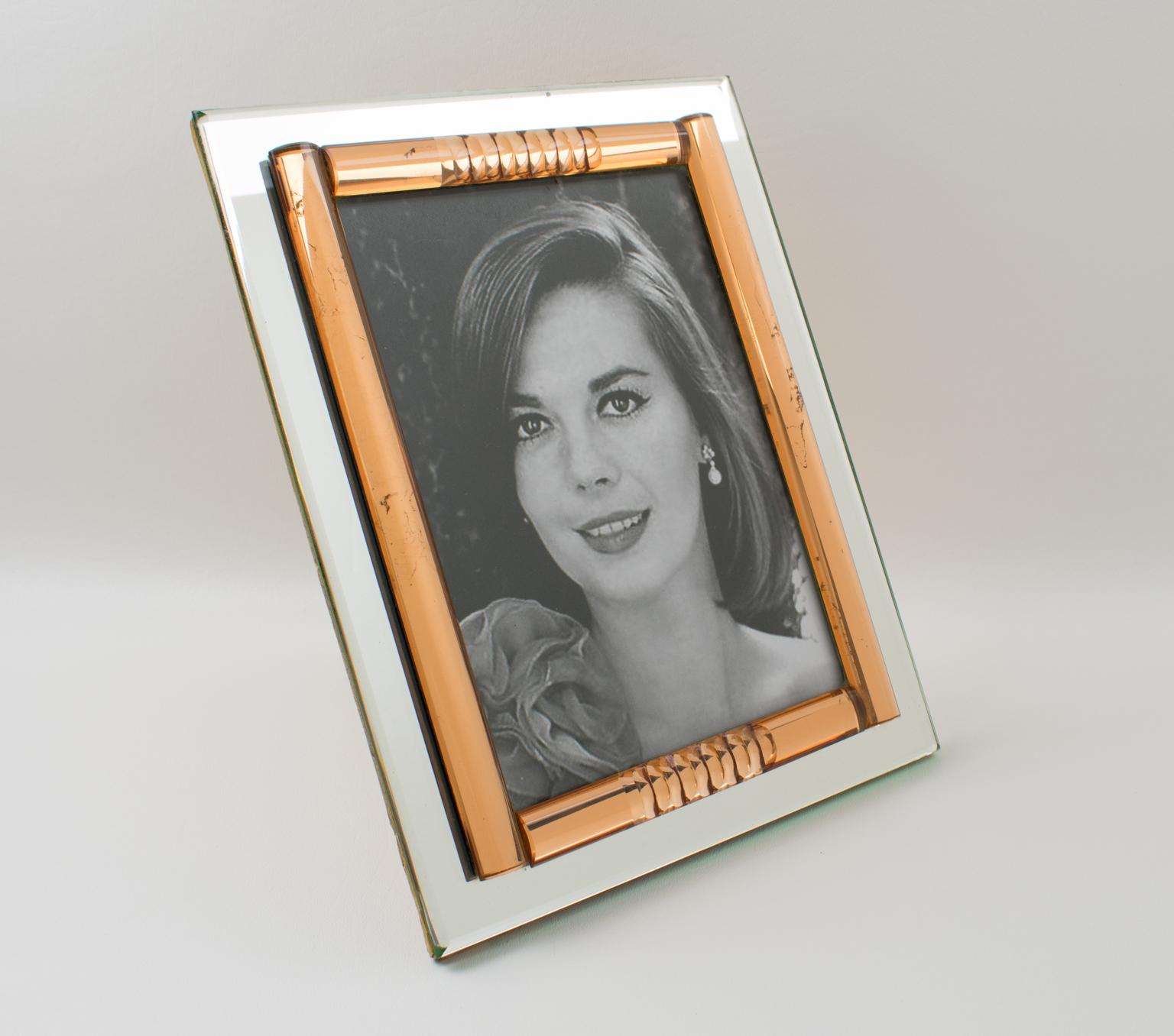 This stunning French 1940s mirror picture photo frame features a deep geometric beveling and domed sides in lovely copper or peach pink tone complimented with silver mirrored glass. The frame can be displayed either in a portrait or landscape