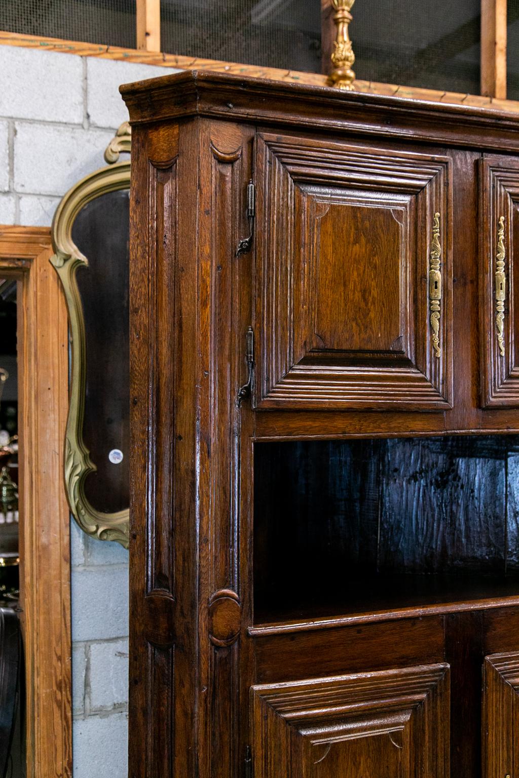 French corner cupboard is oak with carved molded raised panel doors with long brass escutcheons. The exposed peg construction has the original blacksmith steel hinges and chamfered returns with carved molded panels.
  