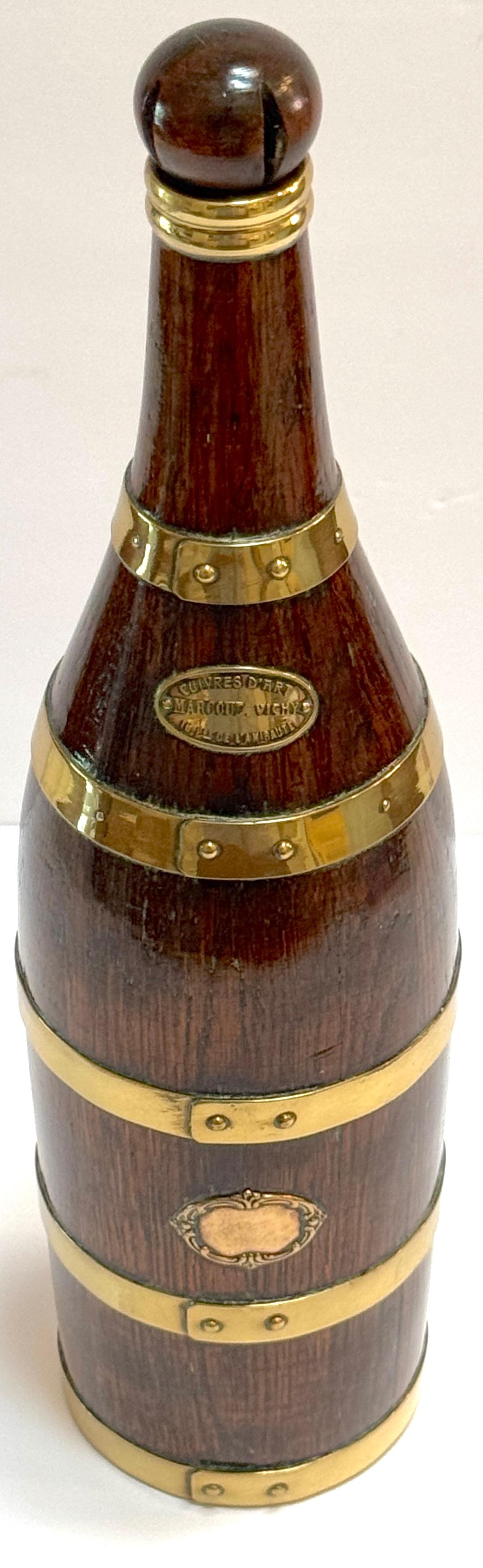 This French Counes Derby Marquot Vichy brass-bound wooden bottle-form box, crafted in France circa late 19th to early 20th century, is a beautifully detailed and finely constructed decorative work. Designed to resemble a liquor bottle, this unique