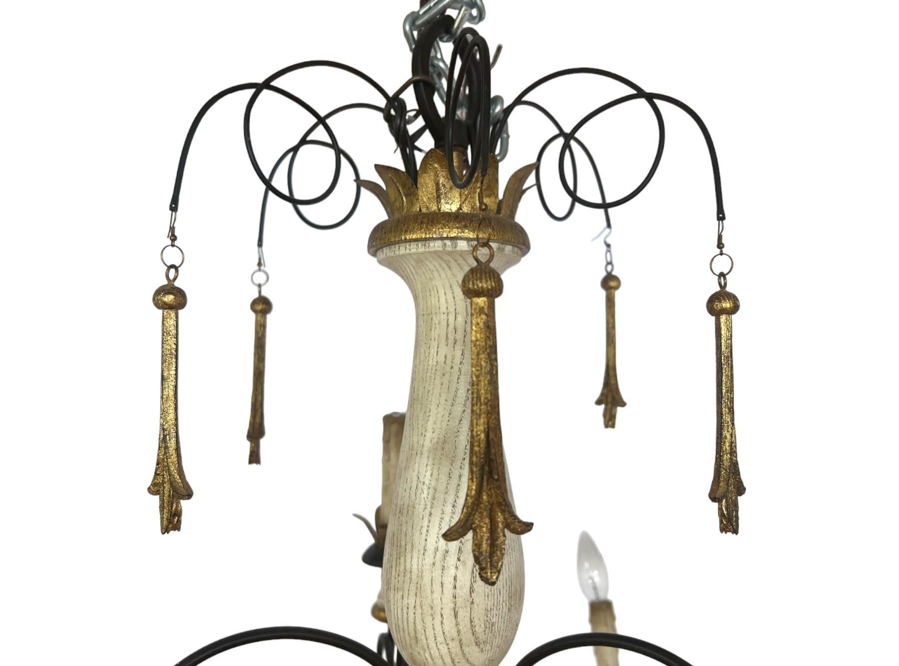 Lustre à 10 lumières fabriqué dans le style campagne française et province toscane, il présente une colonne centrale en bois sculpté avec une patine légèrement vieillie et blanchie à la chaux qui donne à la pièce un caractère authentiquement