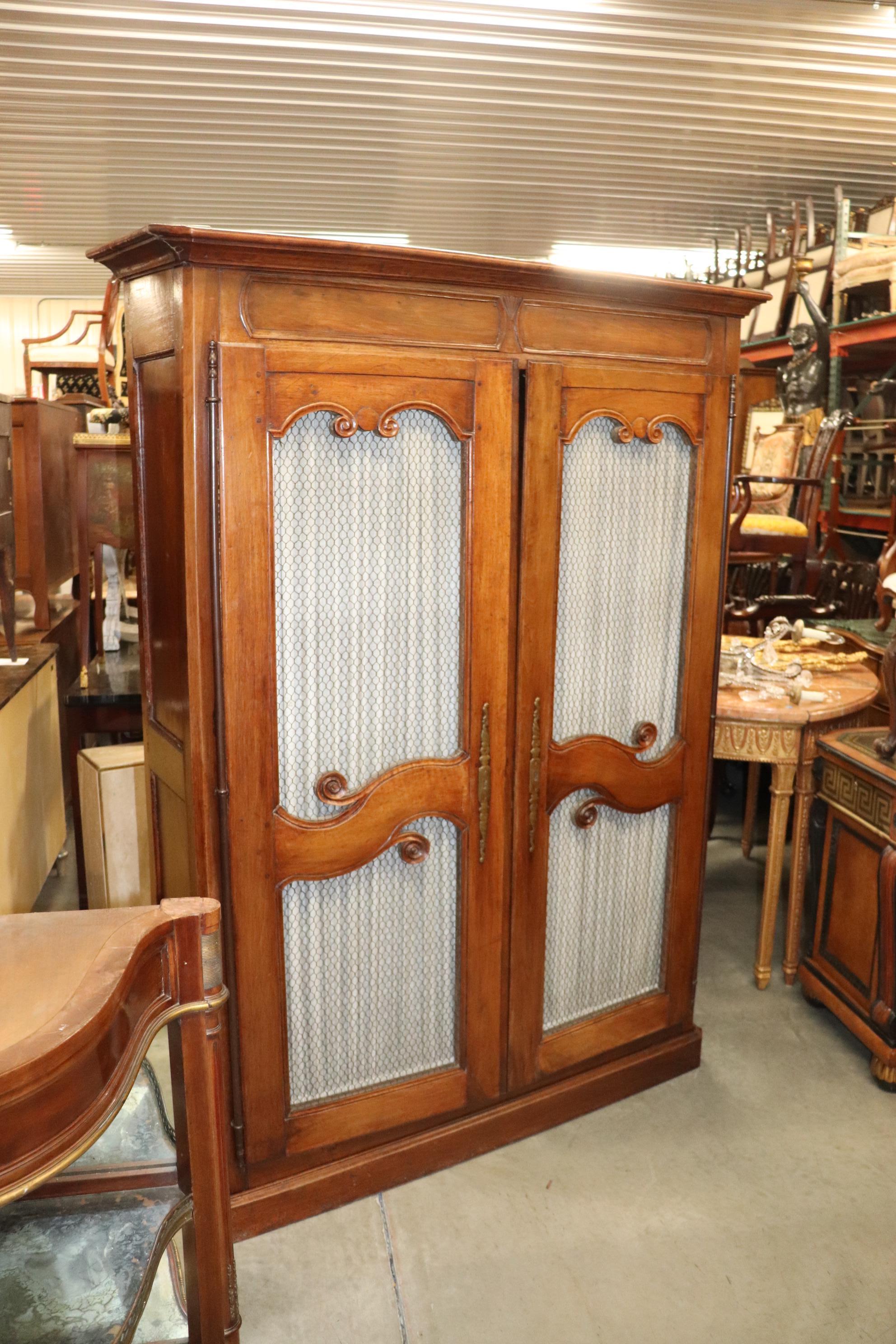 This is a fantastic armoire made during the 1790s -1820s era. The piece has a pair of mesh doors and gorgeous carved details. The armoire is mortice and tenoned and measures 55 wide x 16.5 deep x 74.5 tall. The upholstery can be removed.