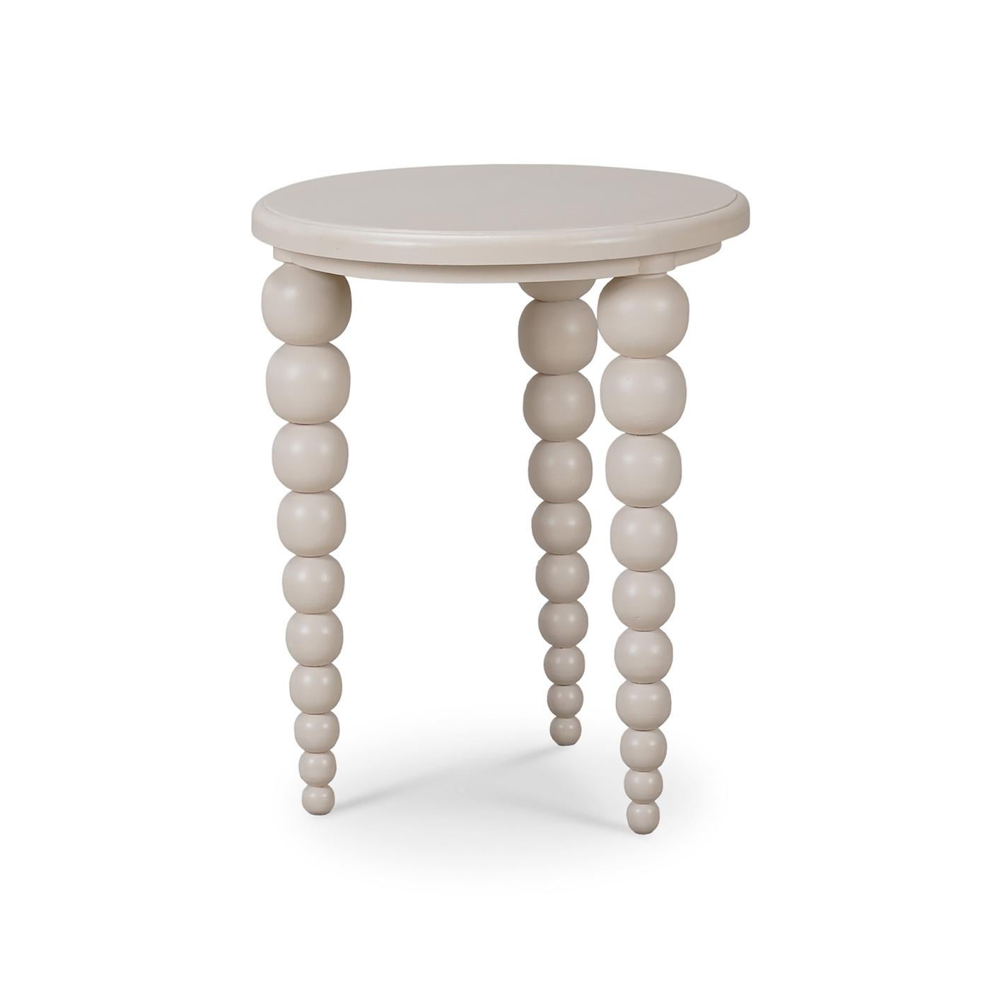 Une pièce unique qui allie sans effort un design contemporain à une élégance ludique. Cette table d'appoint ronde est dotée d'une finition peinte couleur mastic légèrement vieillie et de pieds perlés effilés distinctifs. Le design unique des pieds