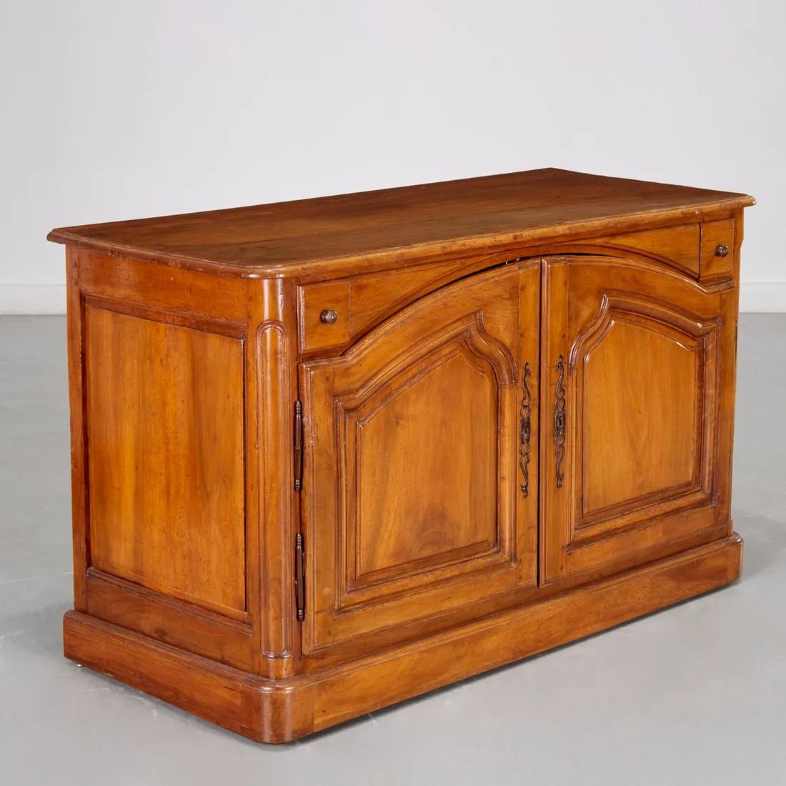 A French Country Buffet de Chasse in blonde walnut, mid-late 18th century, the rectangular wood top with rounded corners, over 2 small frieze drawers and 2 arched paneled doors, concealing a recent group of interior drawers, all in a plinth base.  