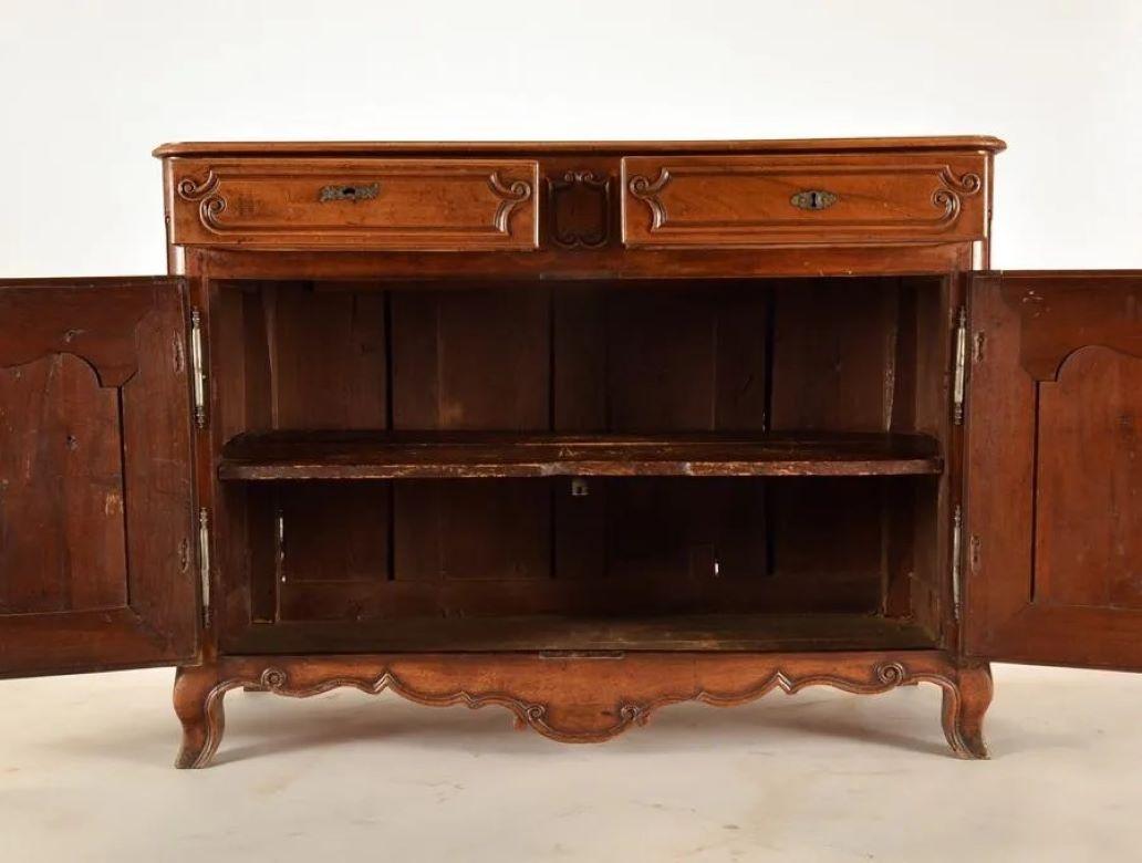 An 18th century French Louis XV period buffet in walnut, with 2 carved drawers over 2 cabinet doors, nicely carved and paneled with original iron hardware and key, all on slight cabriole feet with a scalloped apron. Circa 1770. The piece may have