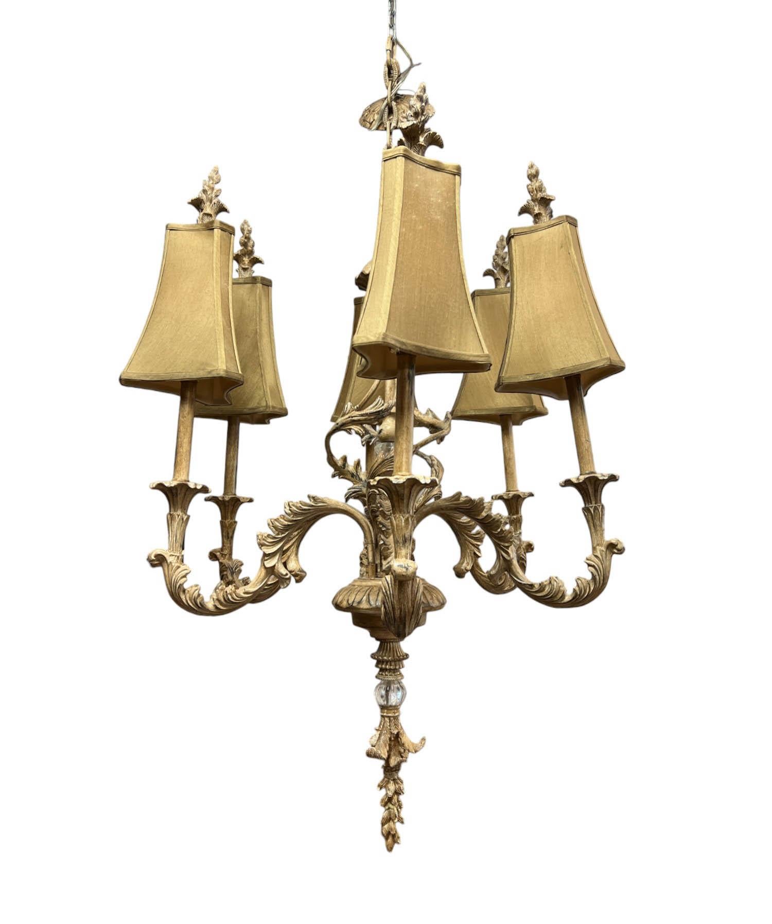 Ce lustre enchanteur incarne l'élégance intemporelle de la campagne française, évoquant le charme rustique et raffiné d'un château européen avec une subtile sensibilité côtière. Ses bras ornés de feuilles d'acanthe sont finis dans un ton de bois