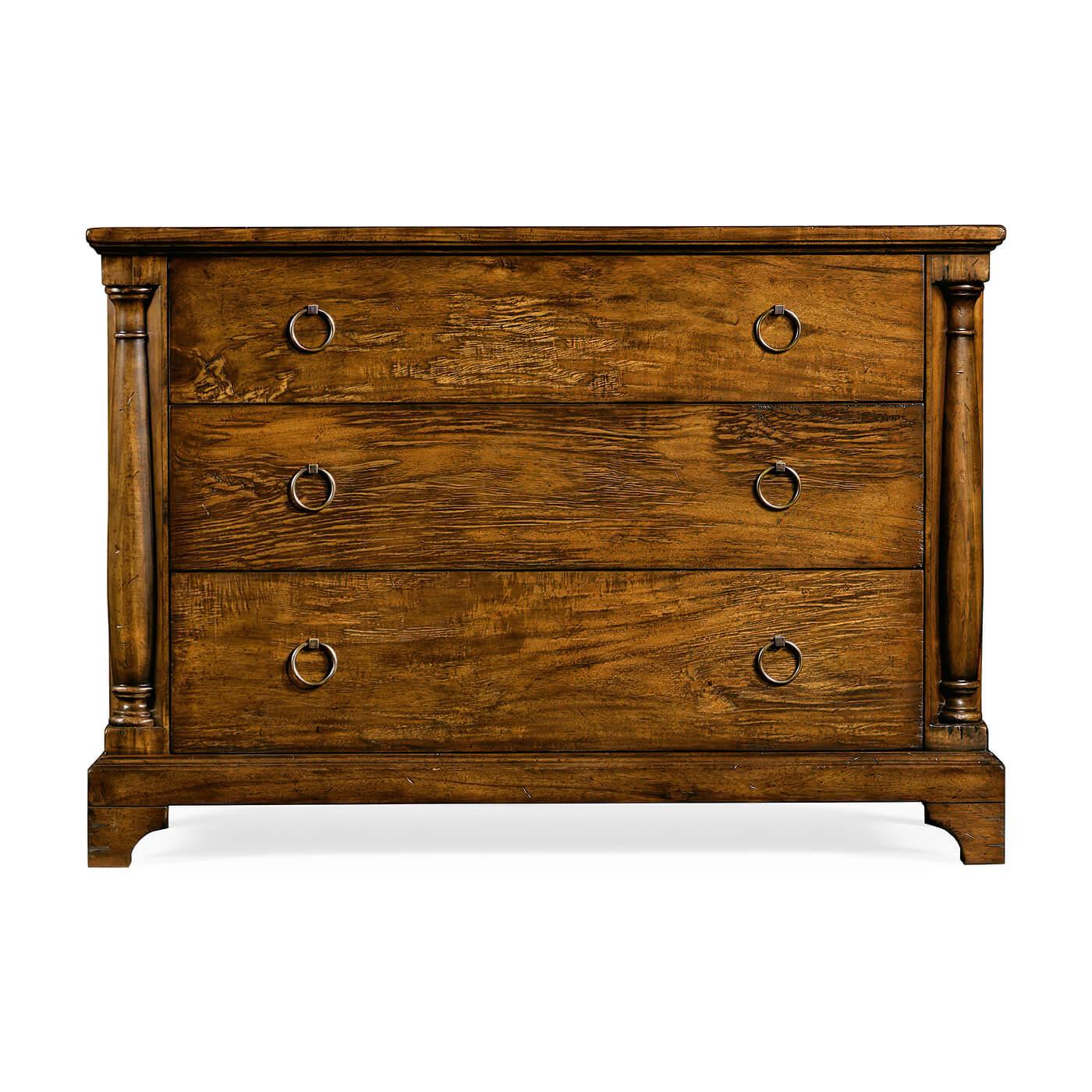 French Country rustic walnut chest of drawers with three drawers, column form styles, with a stepped pedestal base on bracket feet and brass ring handles.

Dimensions: 47.25