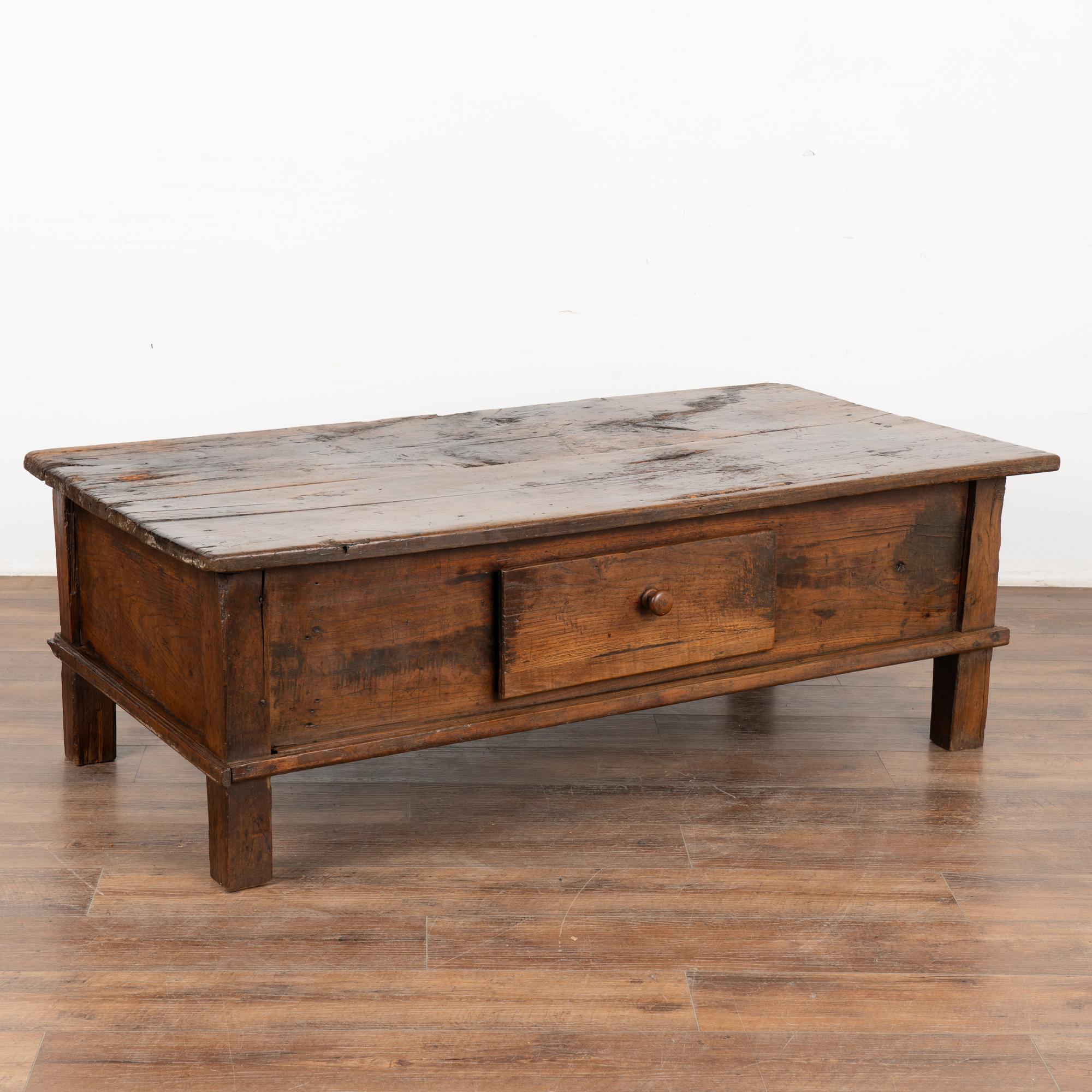 The beauty of this French country coffee table with one large drawer comes from the dep aged patina of the chestnut wood. Every crack, ding, gouge, old knot and stain all add to the depth and richness found in the worn top. 
Restored, strong and