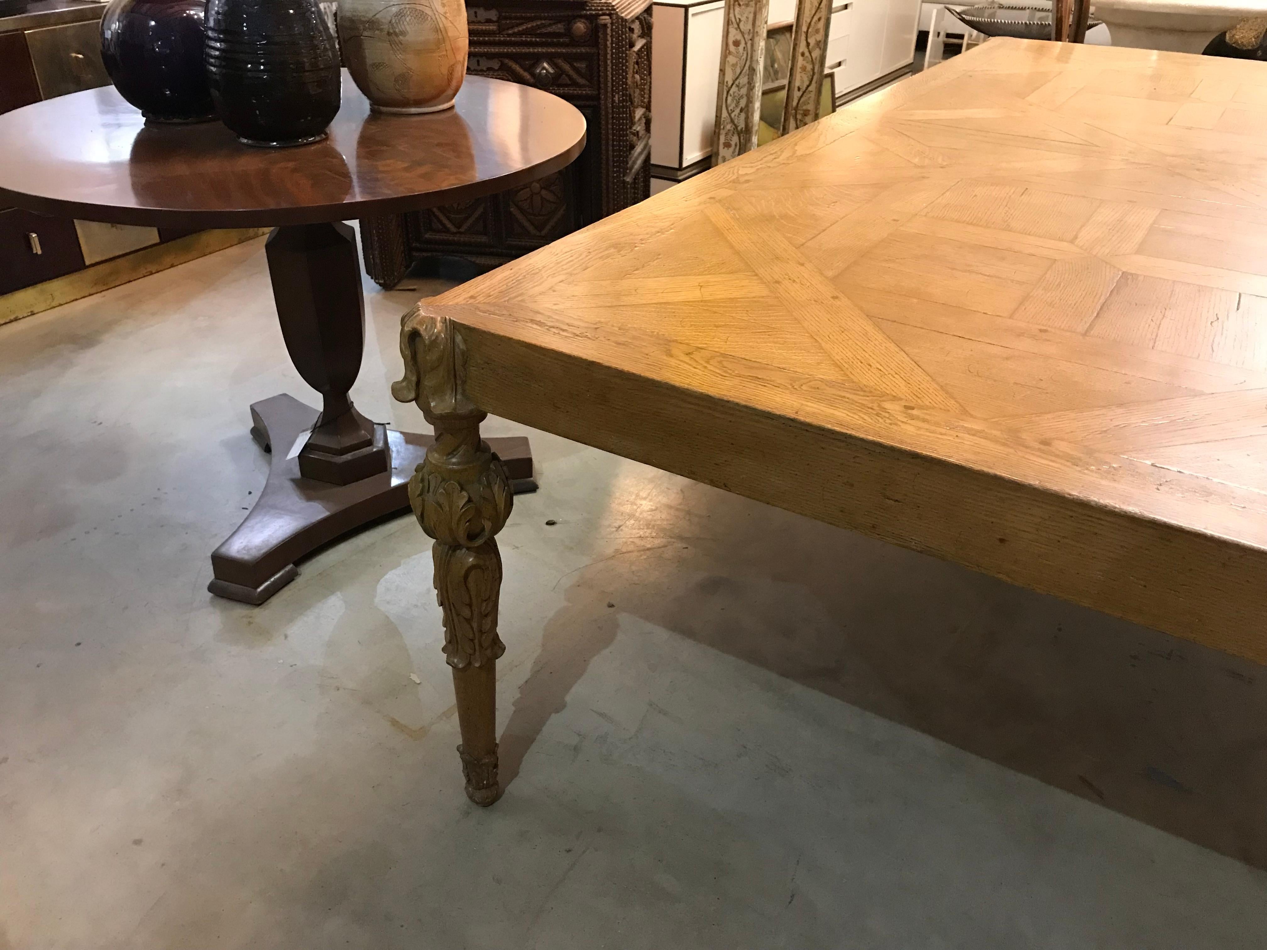 Cette exquise table de salle à manger française présente un mélange parfait de charme rustique et de sophistication élégante. Le plateau présente un étonnant design en parquet, travaillé de manière complexe pour mettre en valeur la beauté du bois et