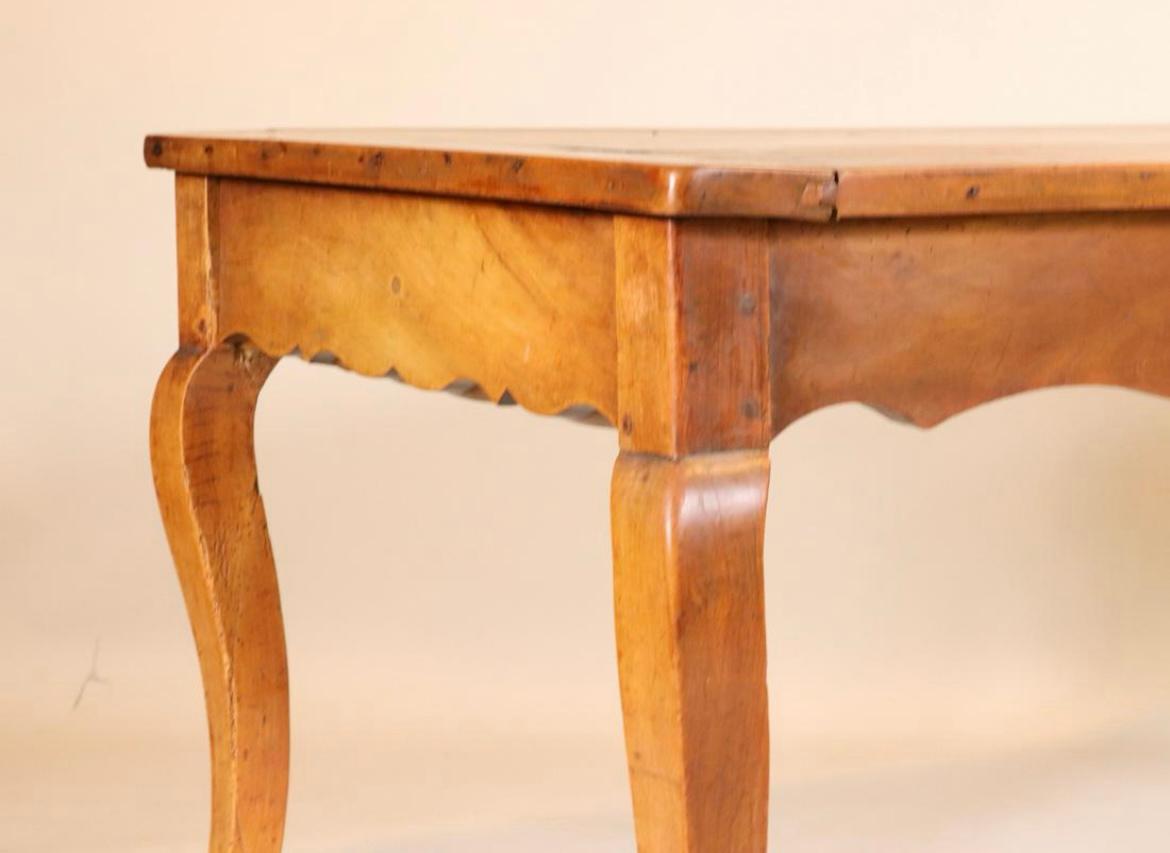 An 18th century Louis XV style farm table in cherrywood with scalloped apron and cabriole legs, a large drawer in each end and a plank top with breadboard ends. Some old repairs and shrinkage gaps in top planks. It 