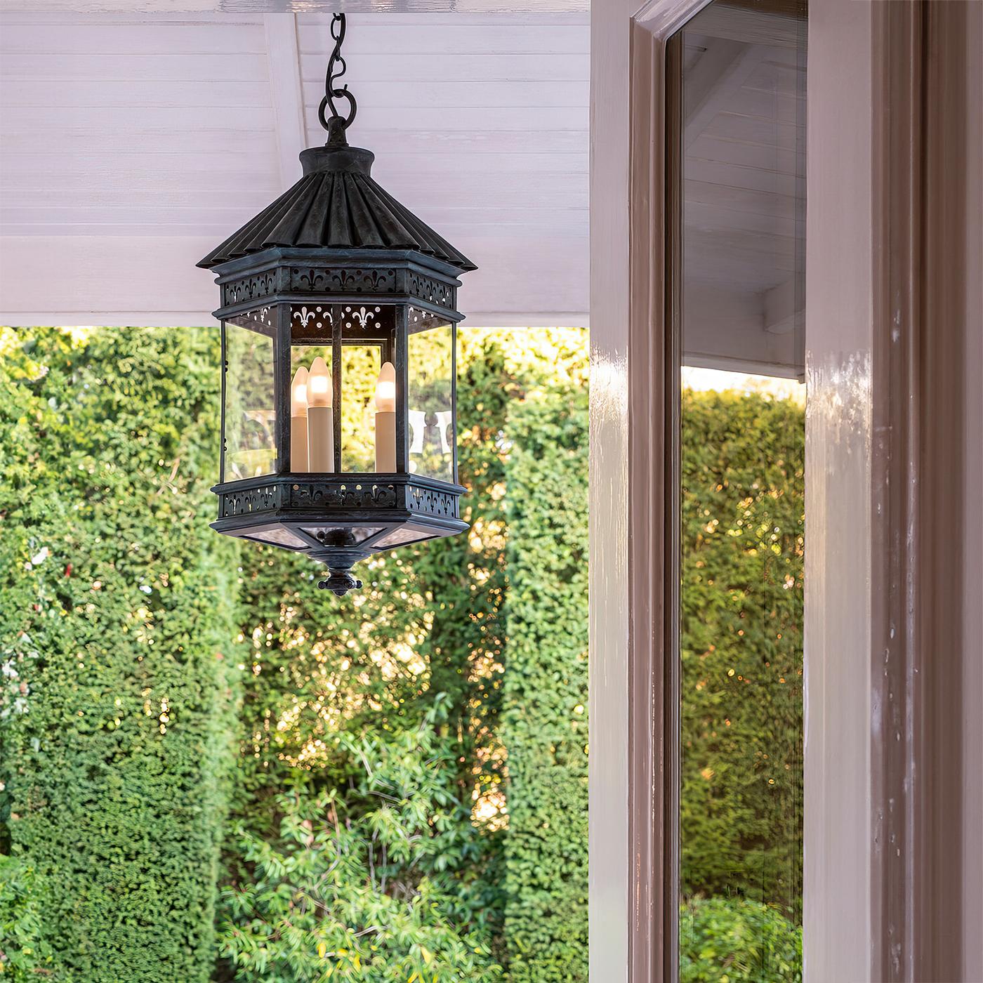French Country Lantern, This hexagonal lantern has a fluted lotus roof, fleur de lis reticulated panel sides, glass sides and door with three lights.

The verdigris bronze finish adds to the elegance of the lantern. UL Listed for wet locations.