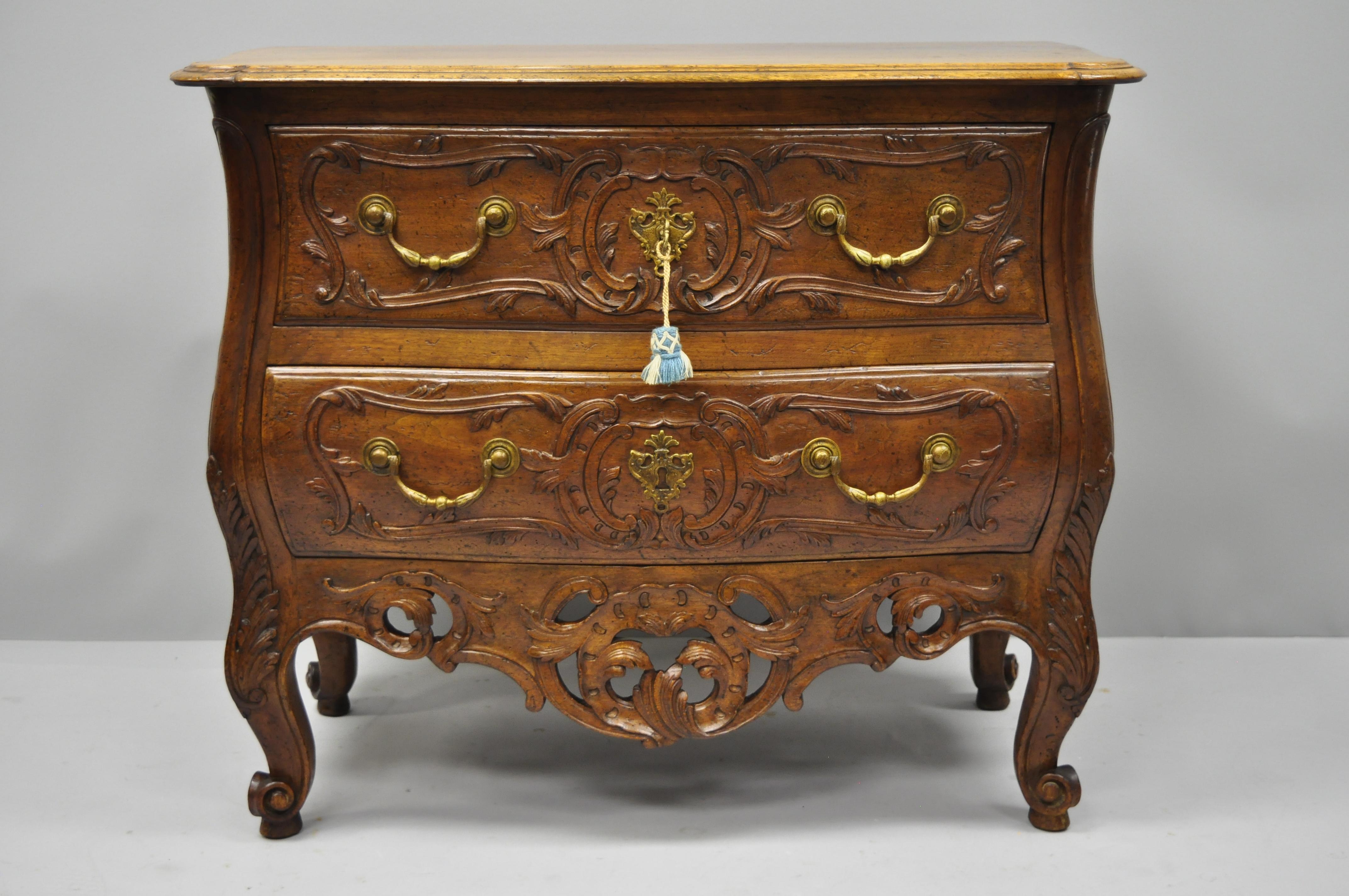 French Country carved walnut bachelor chest. Item features solid wood construction, beautiful wood grain, distressed finish, finely carved details, working lock and key, two dovetailed drawers, cabriole legs, and solid brass hardware, circa early