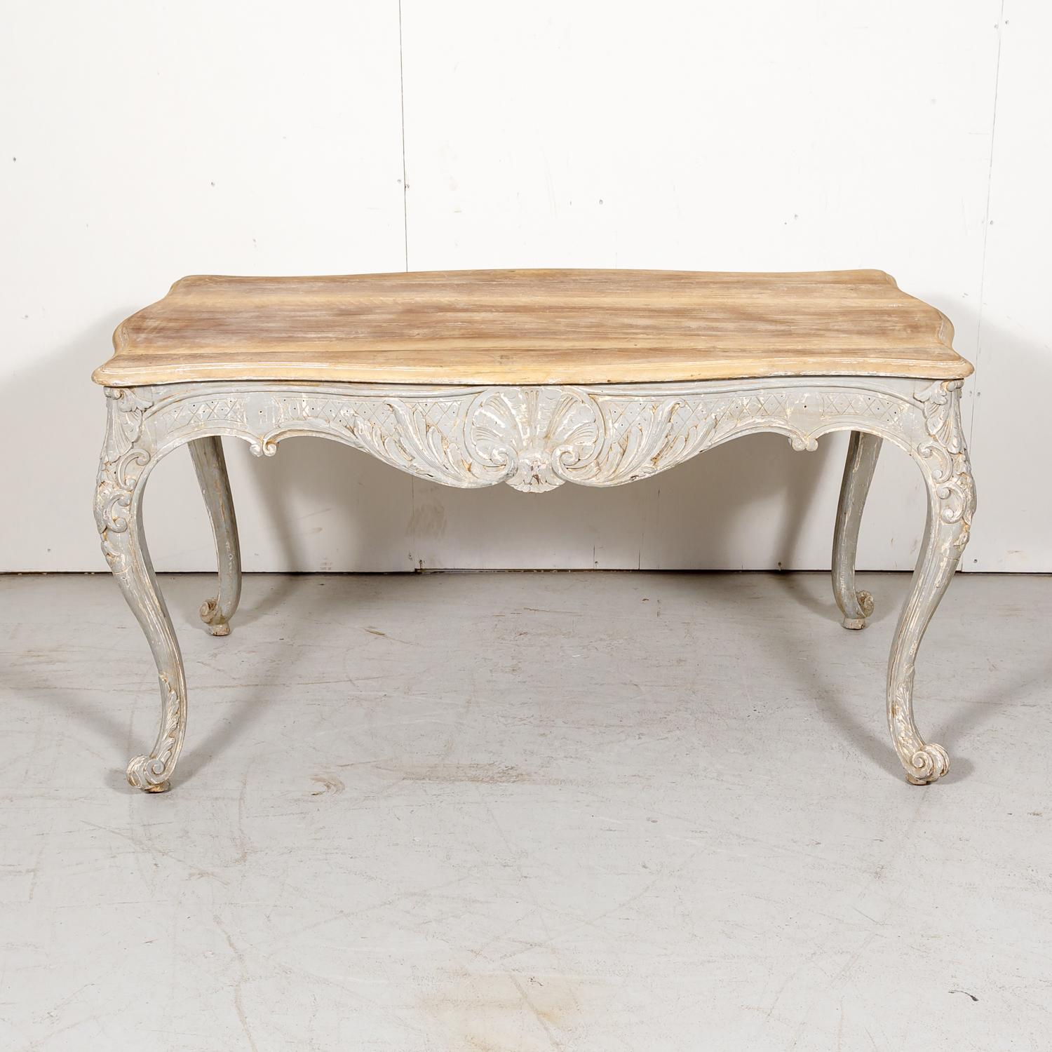 19th century French Country Louis XV style carved and painted solid old growth French oak table handcrafted near Toulouse, circa 1890s. This lovely French table features a bleached and waxed serpentine top above a beautifully carved scalloped and