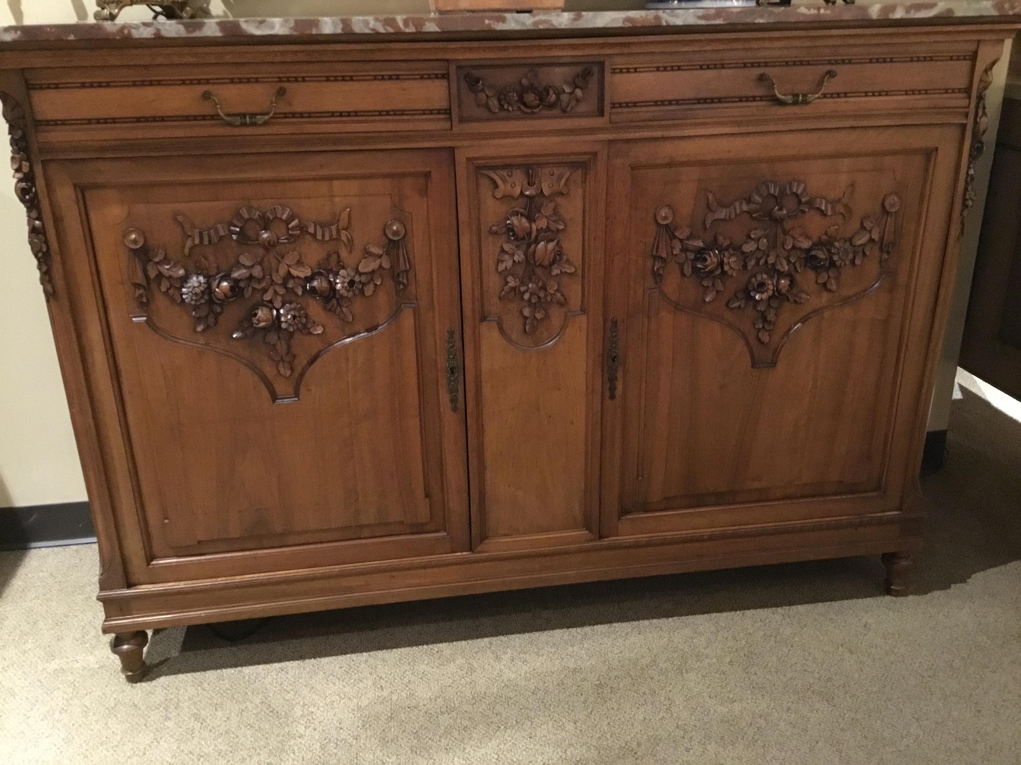 Sideboard in walnut carved with floral and foliate carvings with ribbons and bows.
Two drawers that slide easily above two doors that open to the interior with a 
Shelf for great storage. Original lock and key that functions.