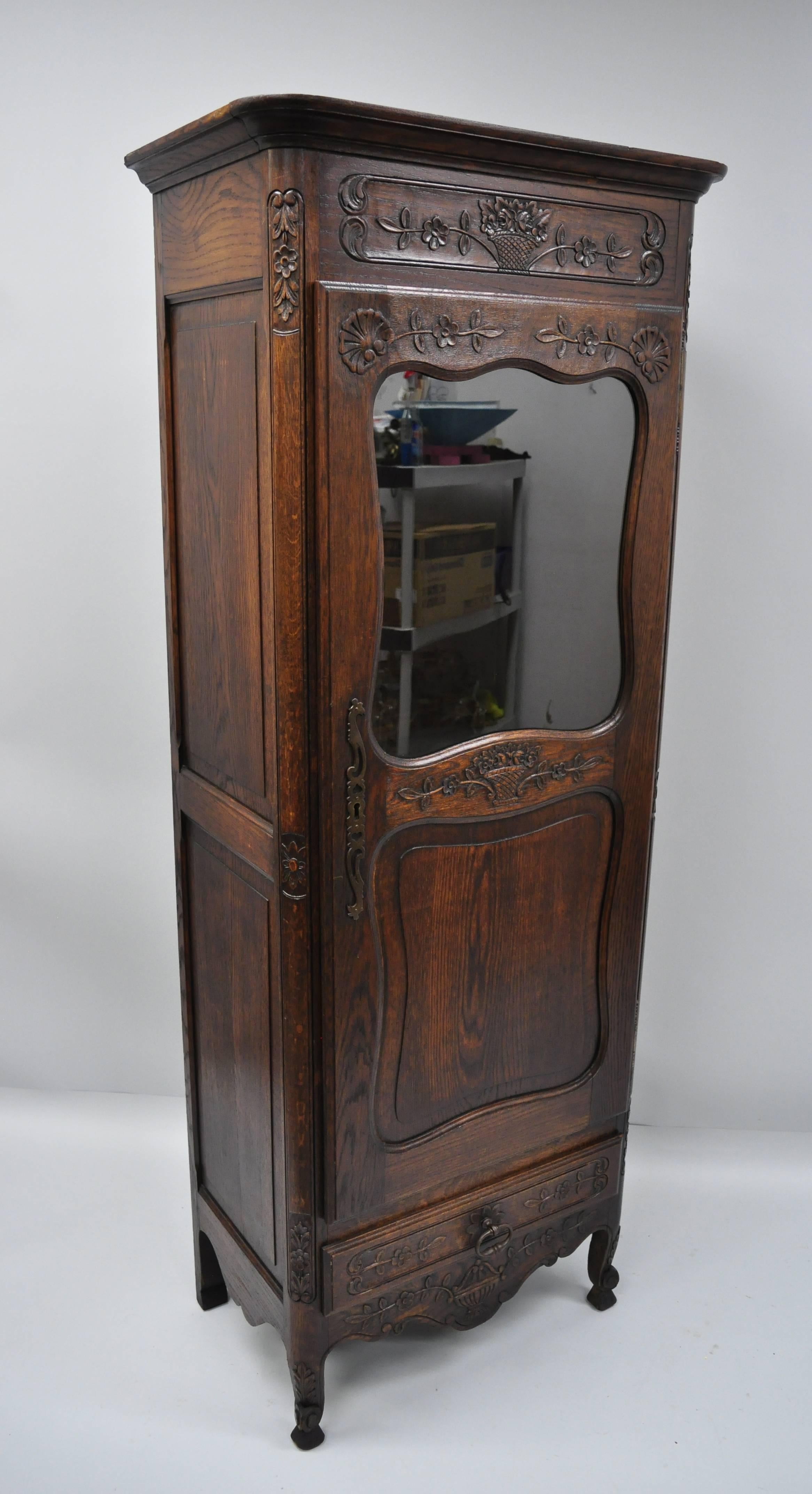 Antique French Country oak wood Curio étagère with floral carvings. Item features solid wood construction, beautiful wood grain, nicely carved details, one glass swing door, working lock and key, one dovetailed drawer, cabriole legs, circa early