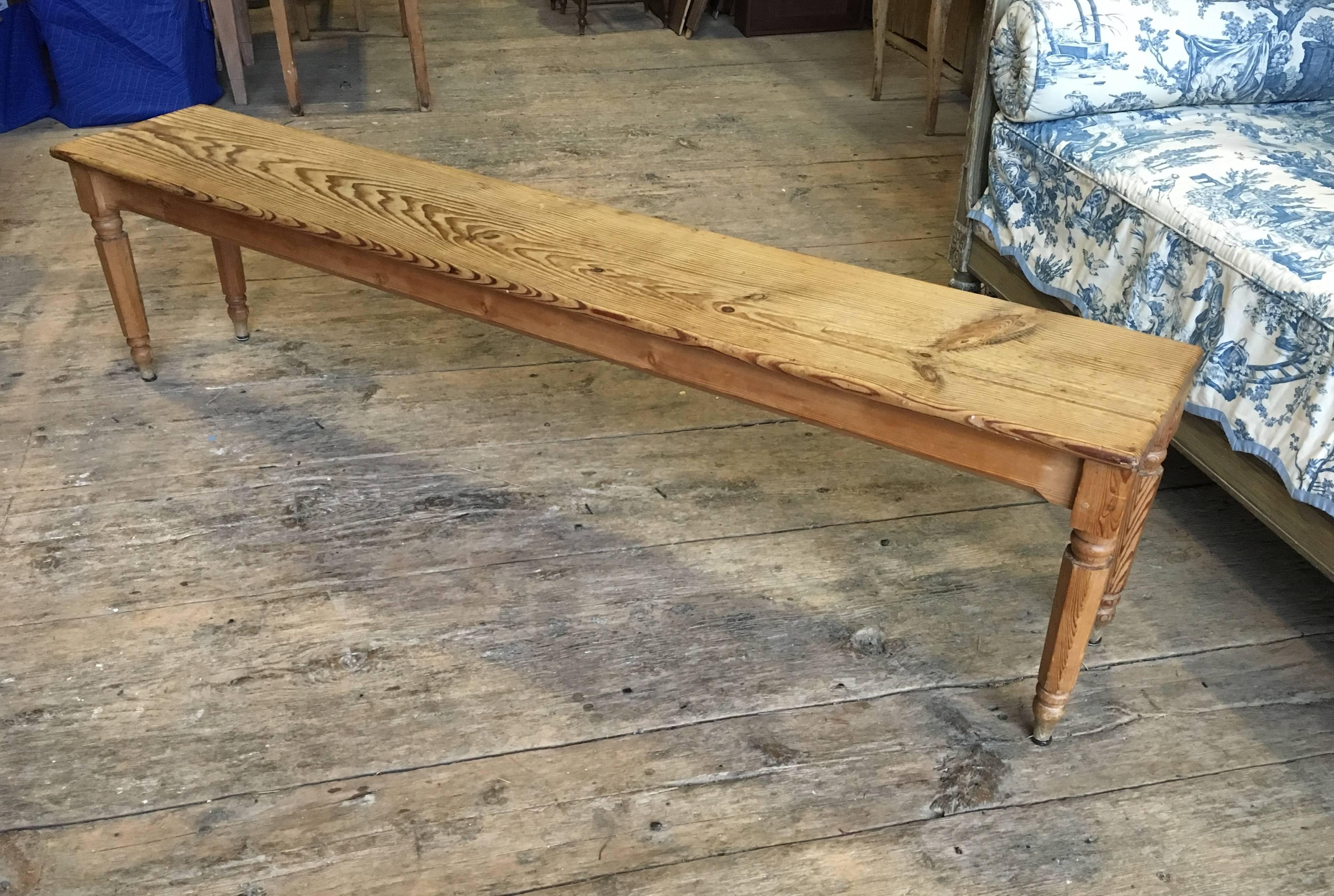 A long French country pine bench with tapered legs and pegged construction, 19th century.