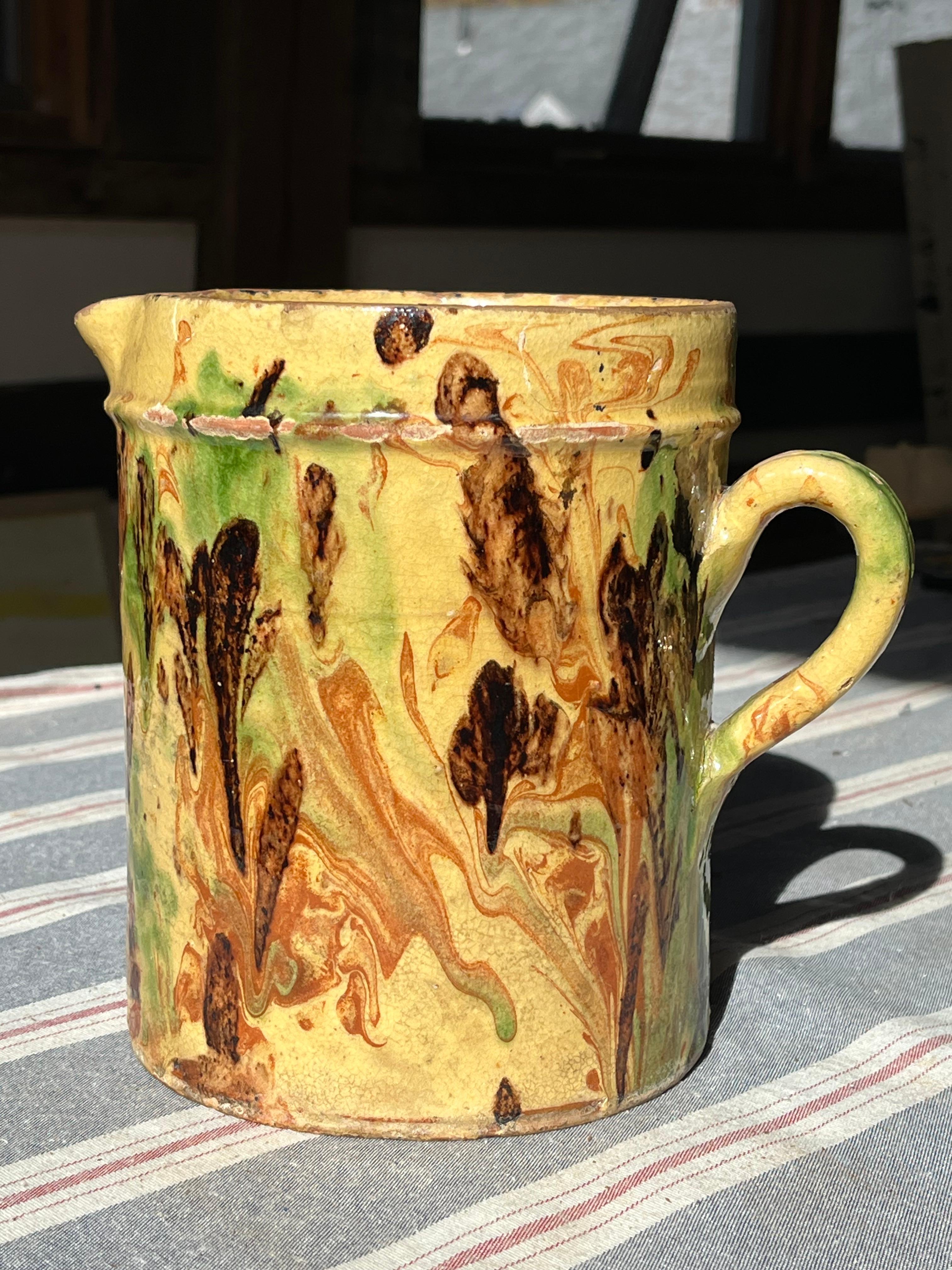 A large French faience Jaspe pitcher from the Savoie region, yellow glaze with green and black, and brown glaze decoration, circa 1890.