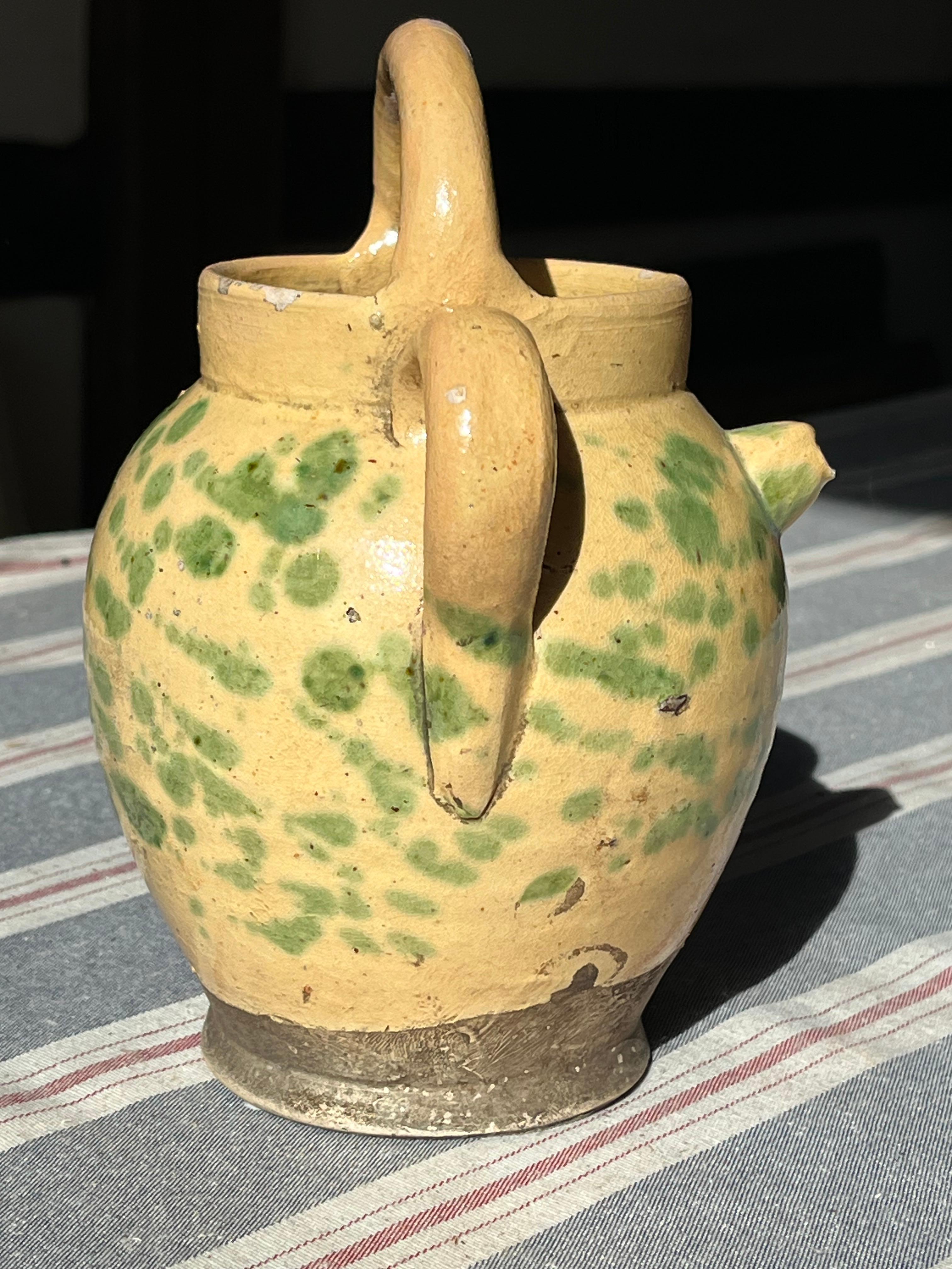 A French faience Jaspe pitcher with 3 handles and a spout from the Savoie region, yellow glaze with green splatter glazed decoration, circa 1890.