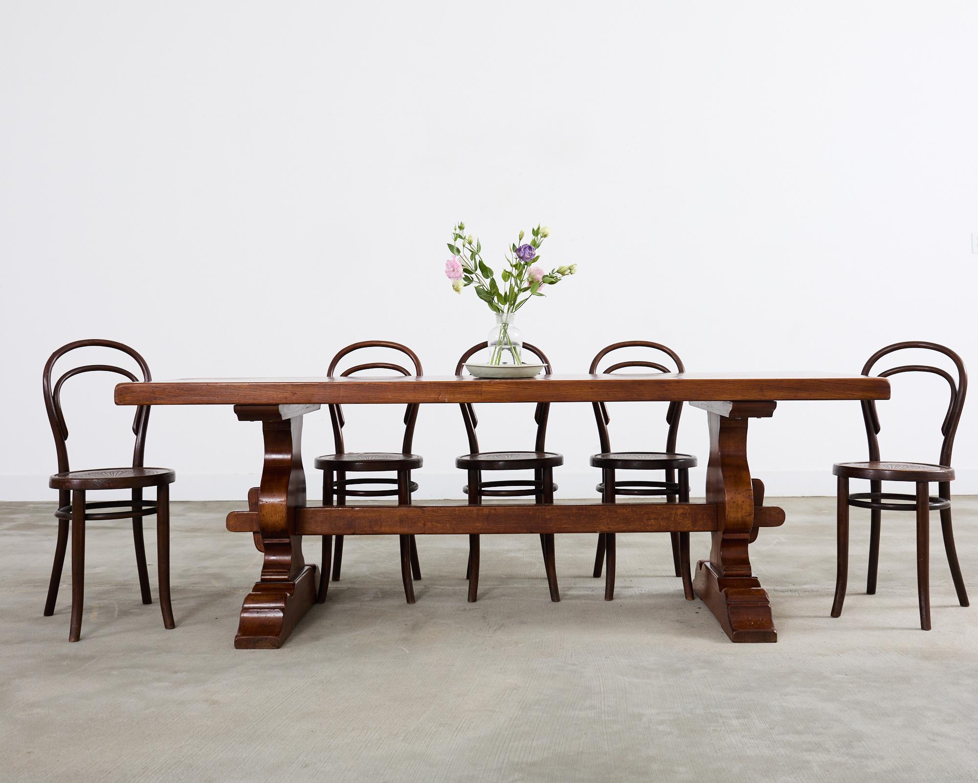 Table de salle à manger classique de style provincial français en chêne. La table est dotée d'un épais plateau en dalles soutenu par un piètement à tréteaux. Le tréteau possède des pieds de forme balustre distincts, reliés par un long châssis à