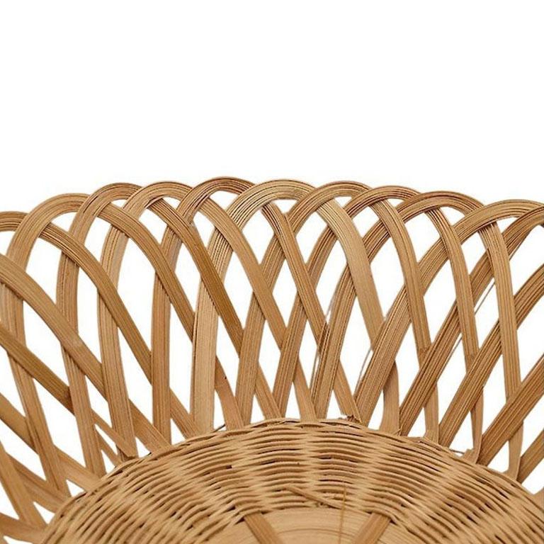 A round woven wicker bread basket or catchall. Created from natural light brown woven wicker, this French Country style basket is round, and features interloping woven pieces of rattan or wicker, with scalloped edges. The base is created from