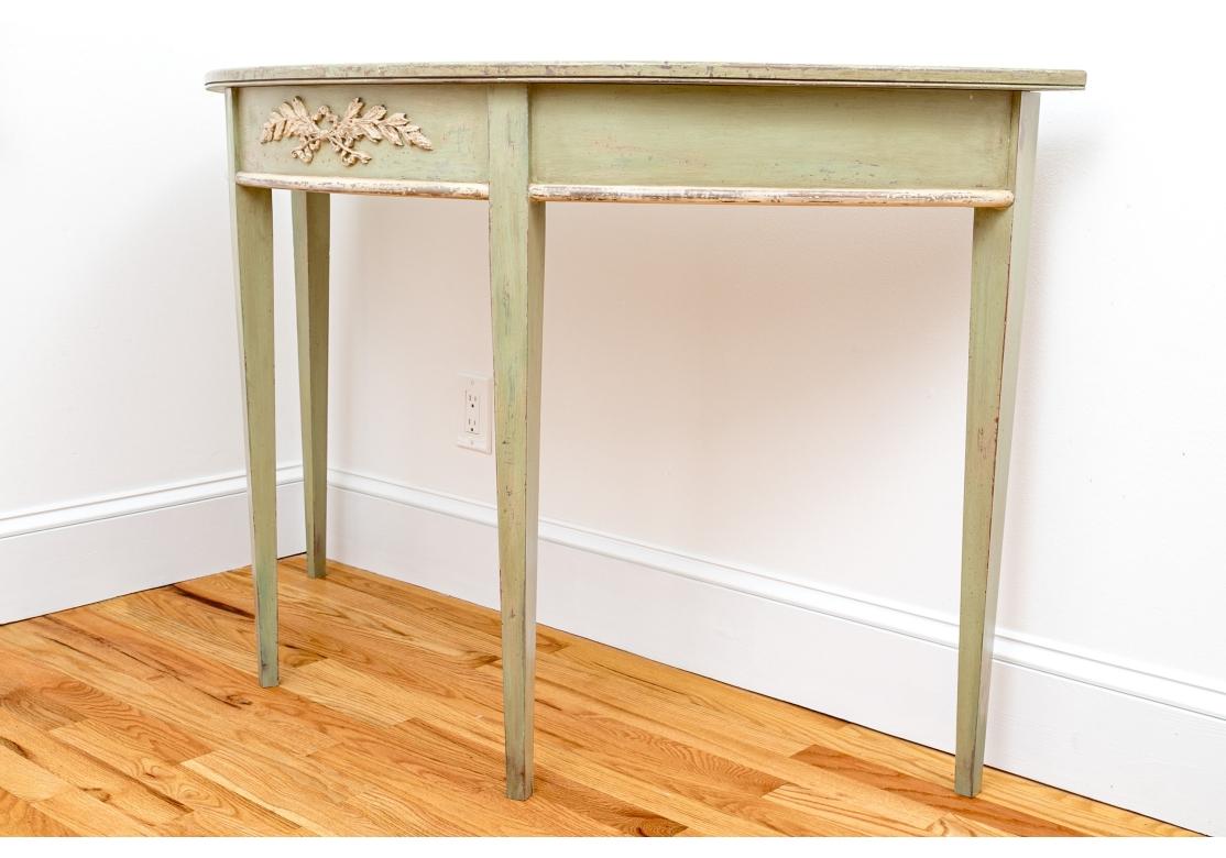 A deep mint green painted console table with a decorative raised swag on the apron center. With an intentional distressed and timeworn patina with losses.

 Dimensions: 32 1/2