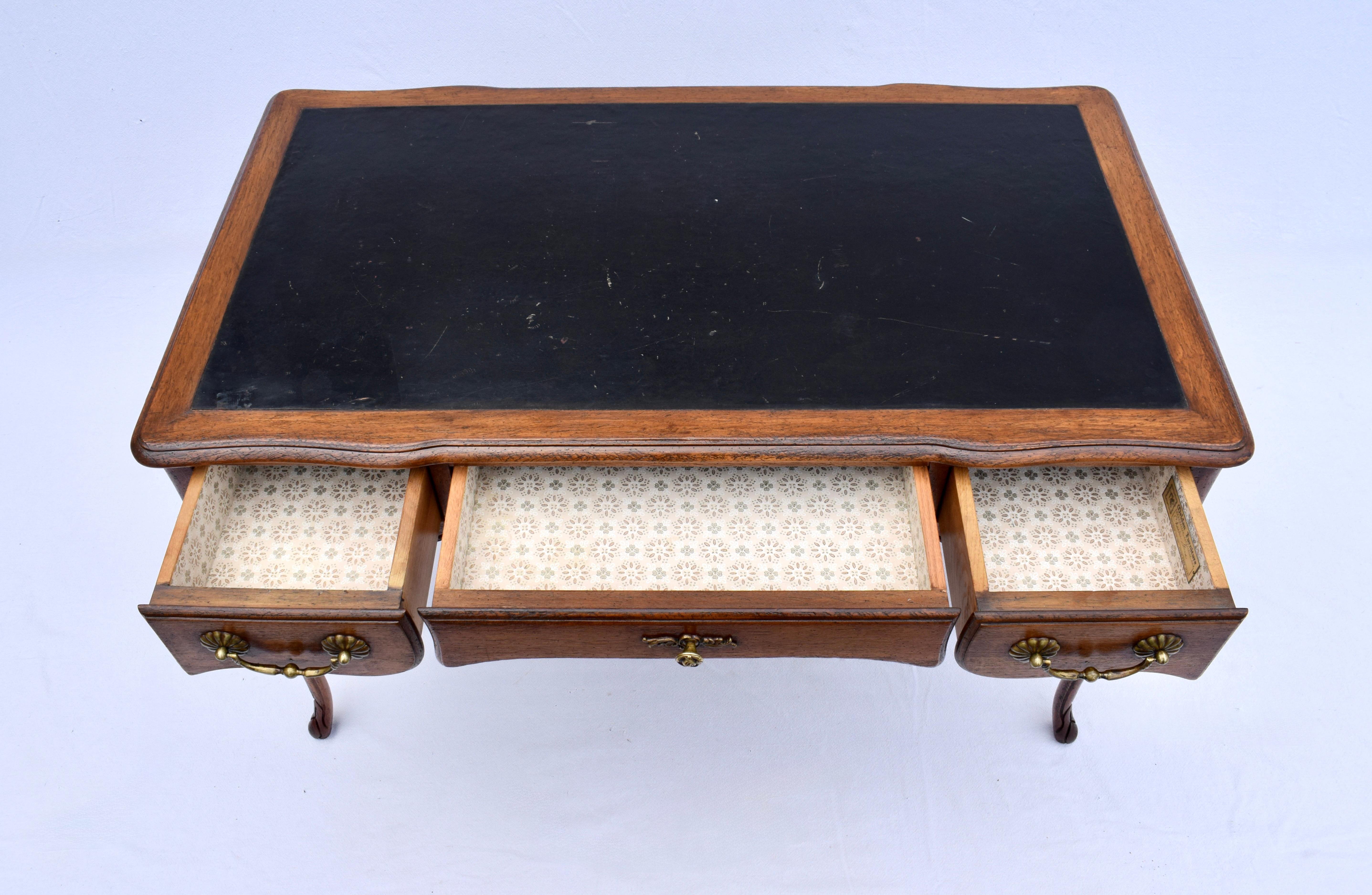 French Country Walnut writing desk with three dovetail drawers & partners styling in the faux drawers to the back side. Handcrafted in the 1950's by Meldan furniture; Hyde Park, Mass. 
Age appropriate wear to the leather top boasts distinct