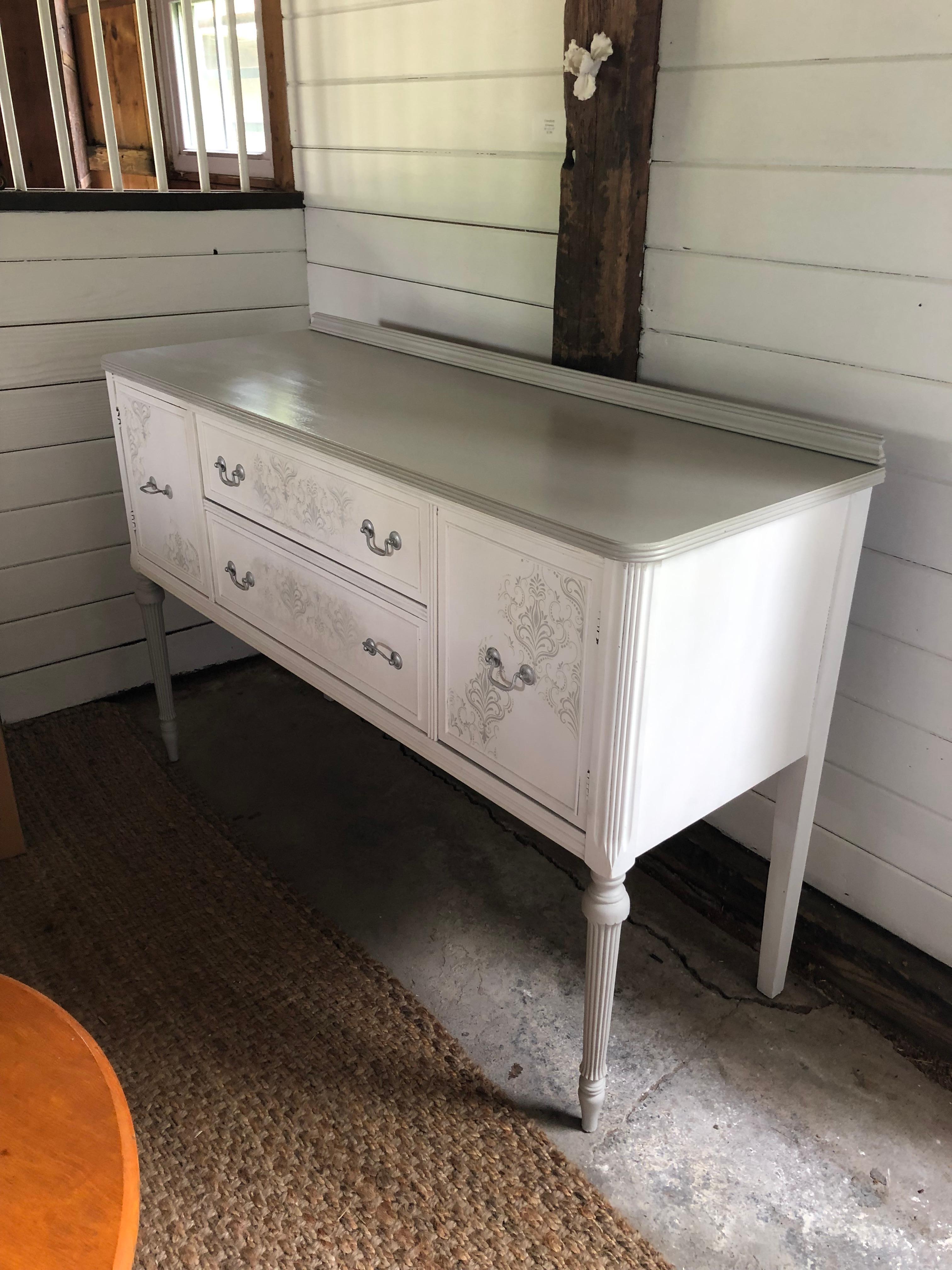 Lovely neutral grey and white hand painted sideboard having excellent storage. Two doors open on each side and flank two drawers. Legs are reeded and very pretty.
