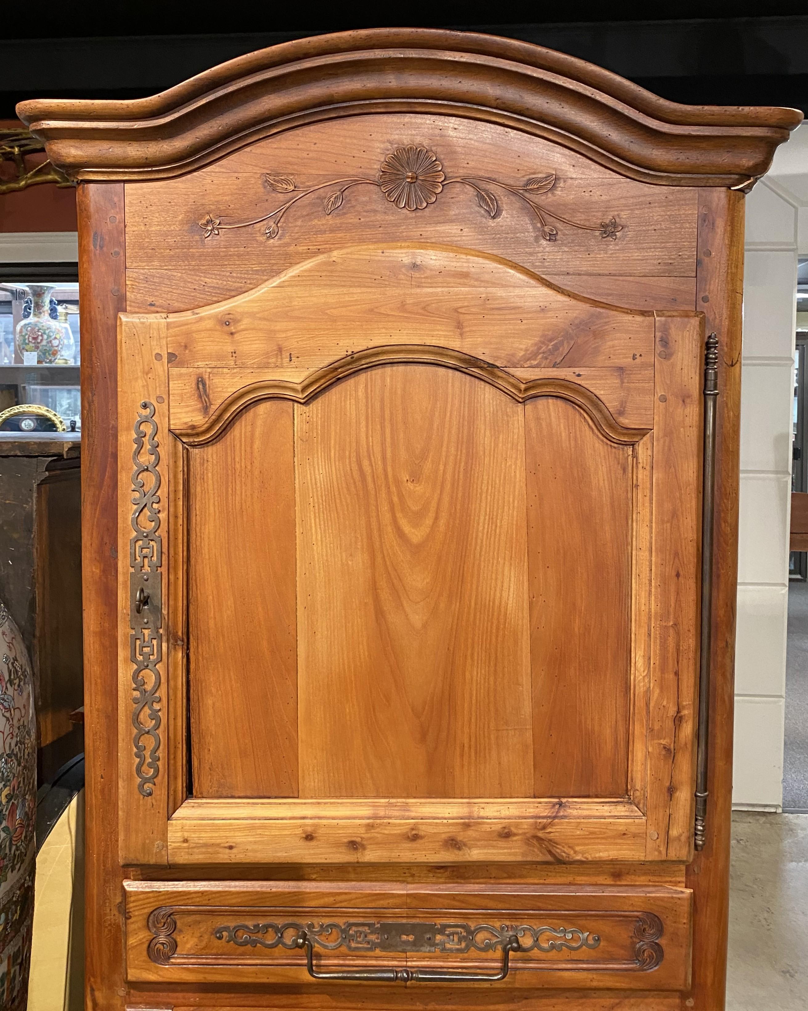 A nice size French country fruitwood two door cupboard with molded arched cornice surmounting two paneled carved doors opening to an upper and lower storage compartments, each with a single shelf, with single drawer between them. The piece has
