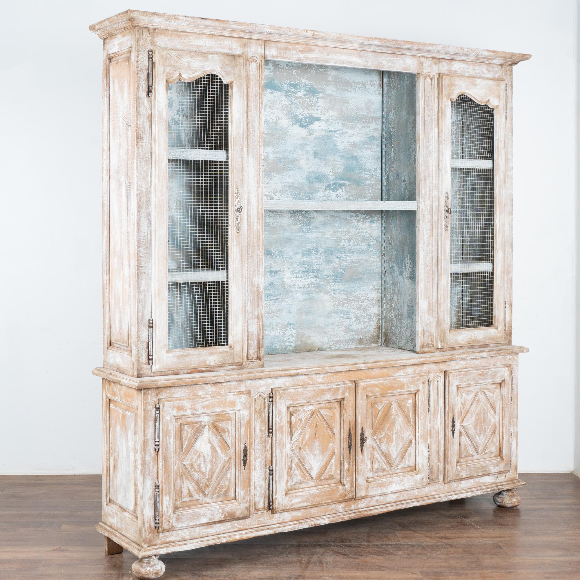 Gran vitrina, librería o vitrina campestre francesa de dos cuerpos.
Madera de roble posteriormente pintada profesionalmente en capas de blanco con un maravilloso acabado envejecido; interior pintado en azul cielo/blanco también envejecido.
Sección
