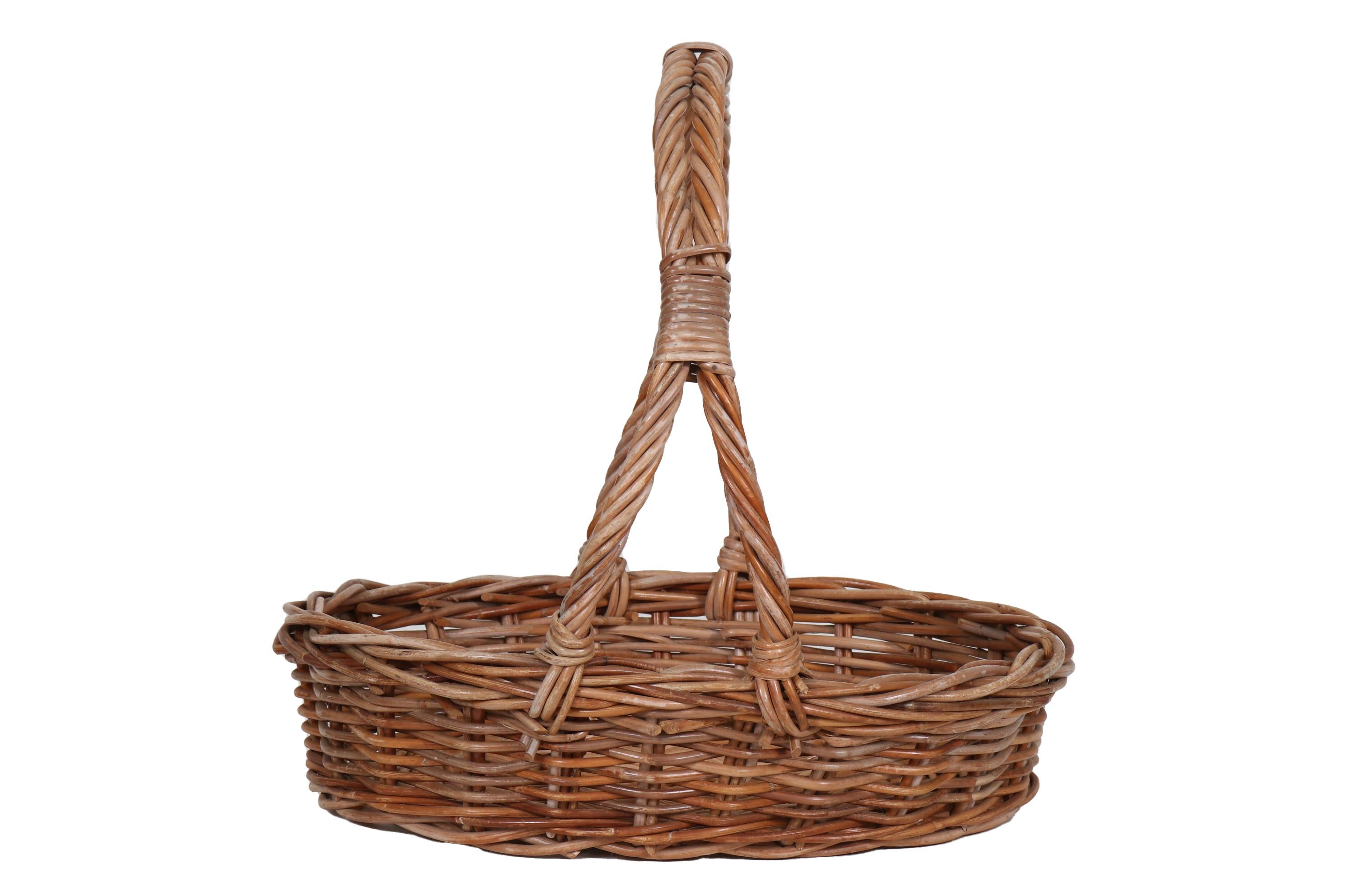 A French country wicker gathering basket. Made of woven rattan with two tall, twisted handles bound together.