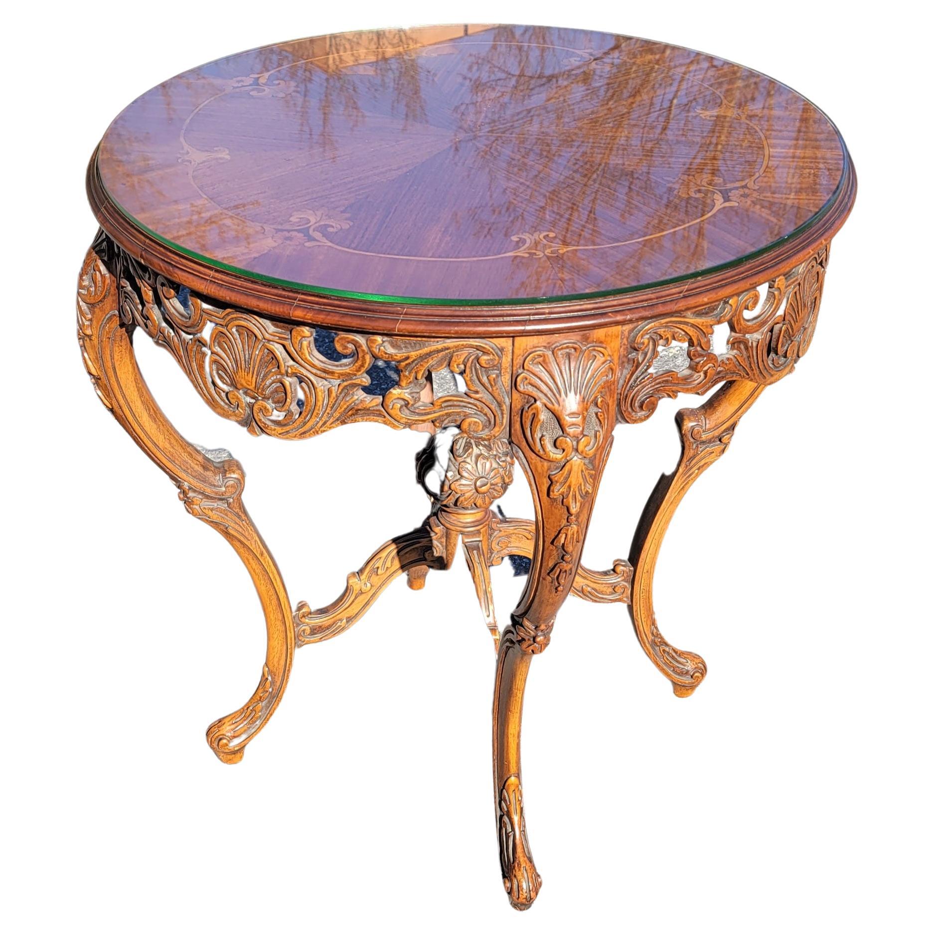 A French Court Galleries by Tonk Louis XVI Style Marquetry and Carved Mahogany Center Table with protective Glass Top.  Richly detailed Inlaid veneer top above a conforming apron with ornate scroll-carvings. Intricate carvings on apron  and cabriole