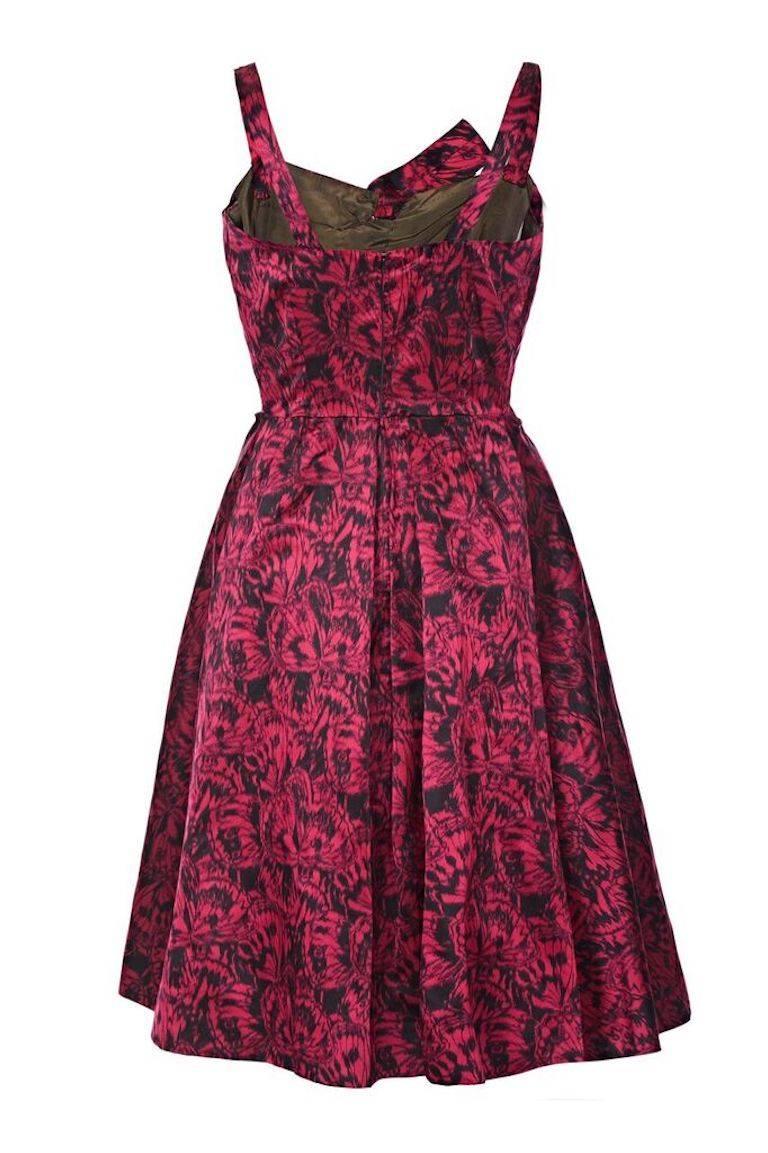 Cette opulente robe de soirée en satin de soie des années 1950 de Perrine est d'une construction exquise et d'une superbe qualité. Le luxueux satin rouge profond est orné d'un imprimé inhabituel d'ailes de papillon et est magnifiquement taillé pour