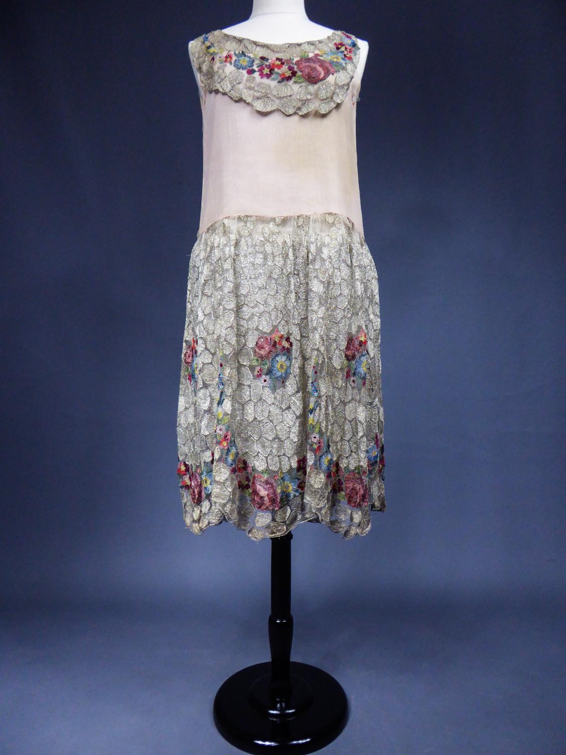 Circa 1920/1925
France

Evening dress in powder pink muslin and embroidered tulle from the Art Deco period around 1920/1925. Low-waisted straight dress and pleated skirt of coton tulle embroidered with roses and silver dots. Bustier in powder pink