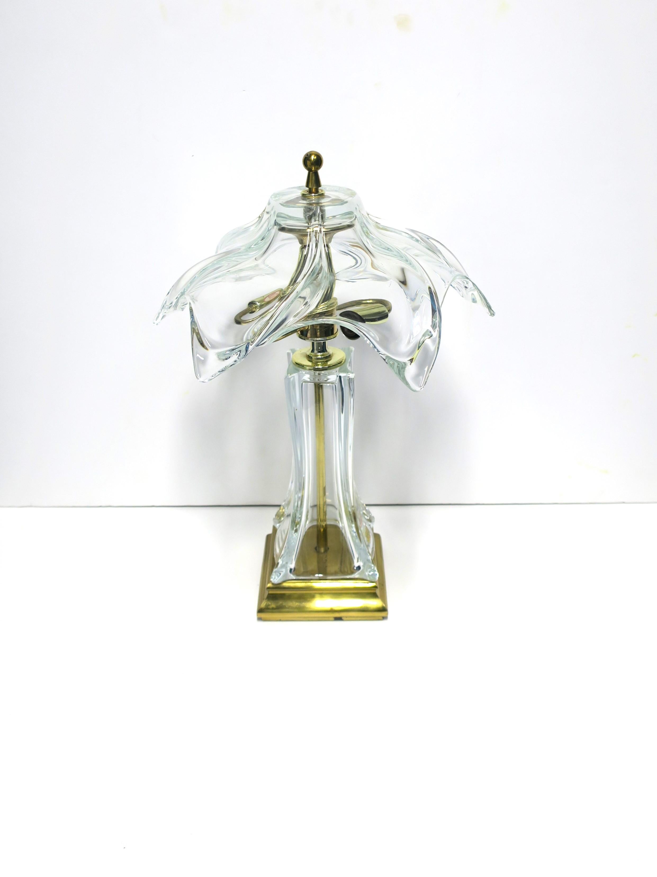 A French crystal and brass desk or table lamp in the modern and Art Nouveau design styles, circa 1960s, Paris, France. Lamp has a French crystal shade and body, solid brass rod at center, and a lacquered brass base. Light holds two chandelier